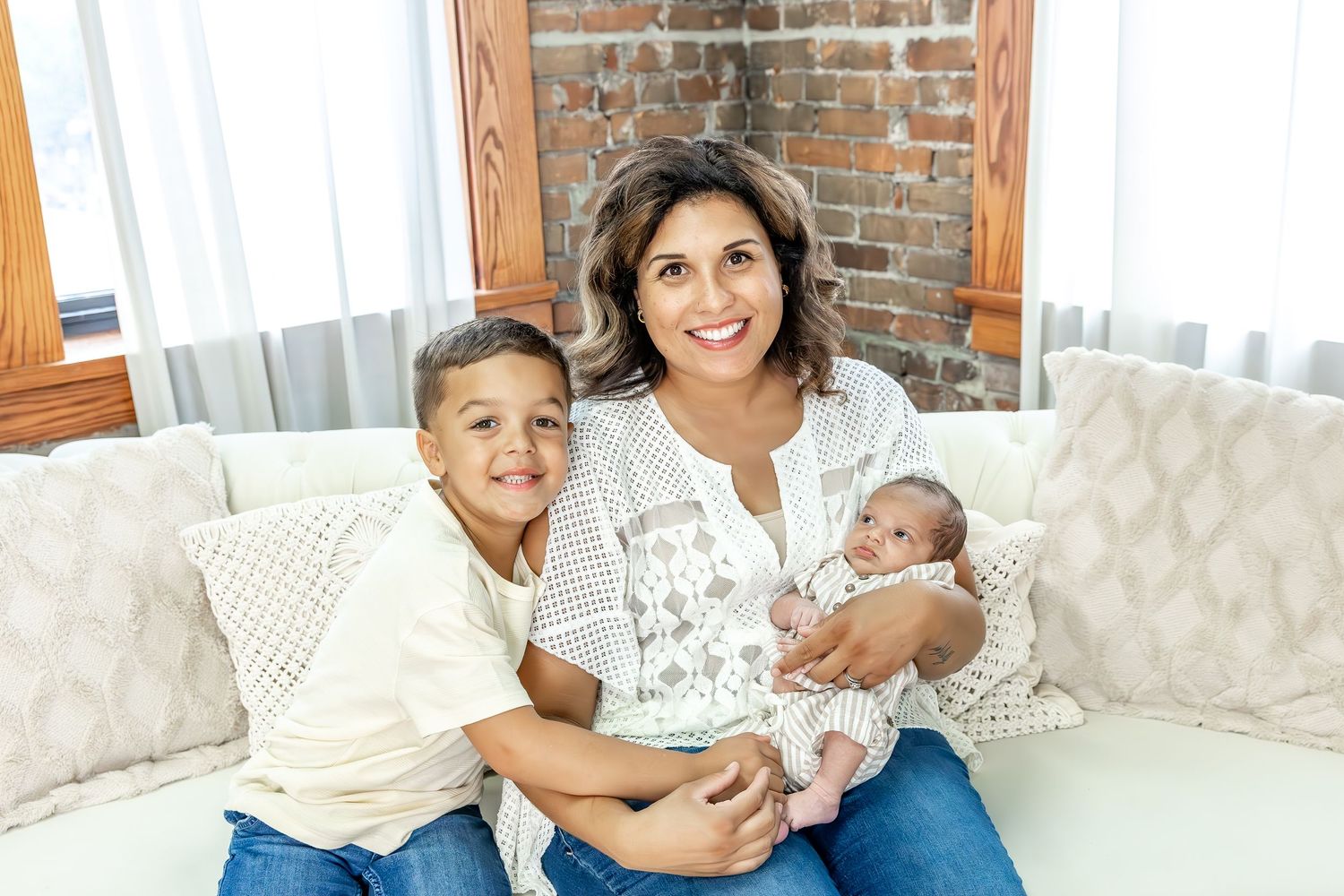 A family poses together on a comfortable white couch in a rustic-styled room.