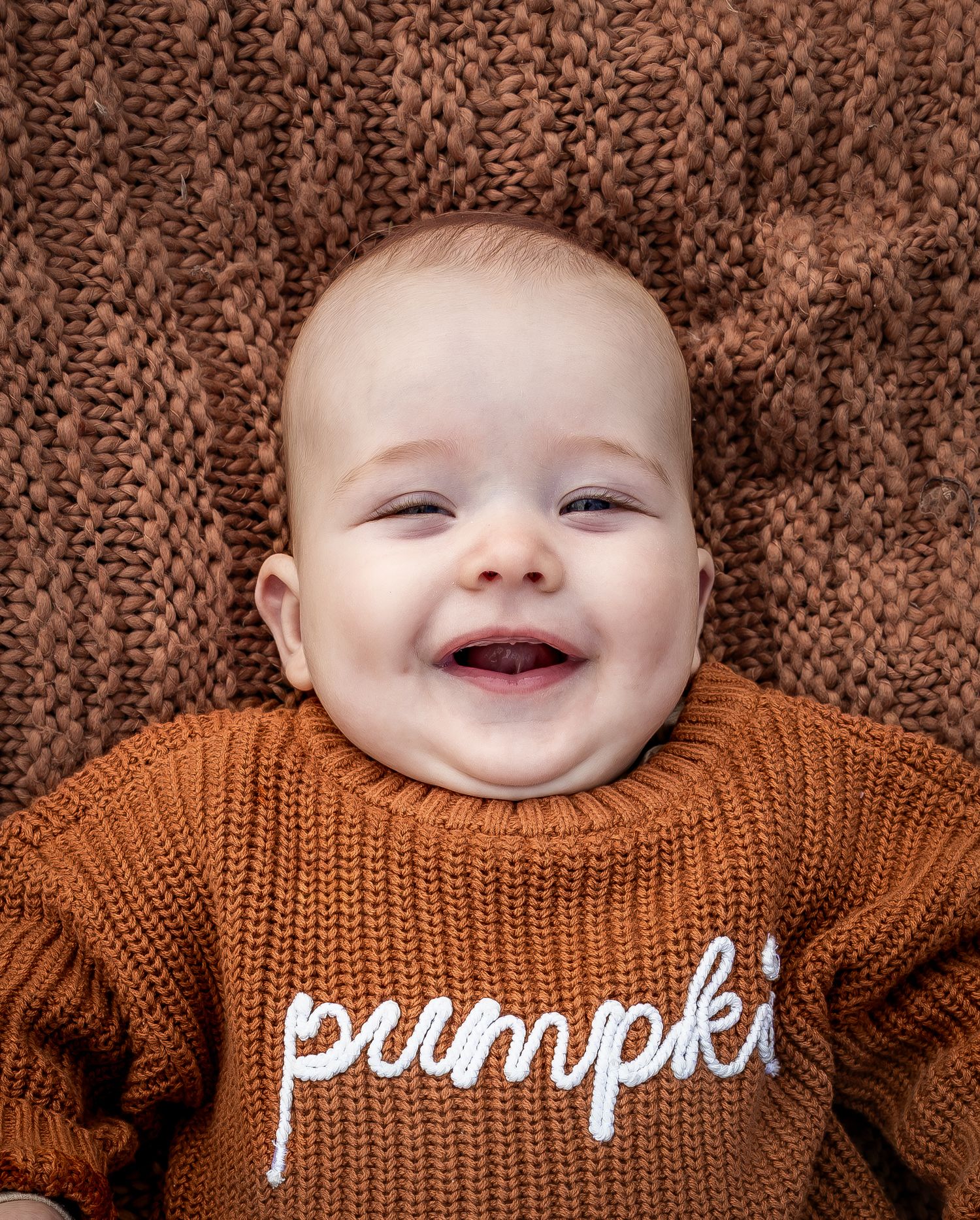 Close-up sequence of a baby wearing a brown knit sweater with text.