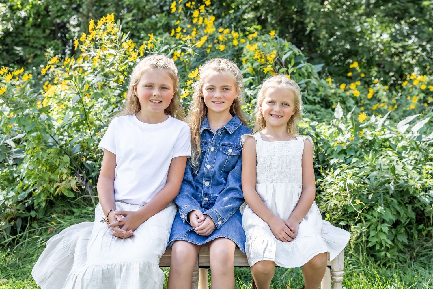 Children sitting together outdoors with yellow wildflowers blooming in the background.