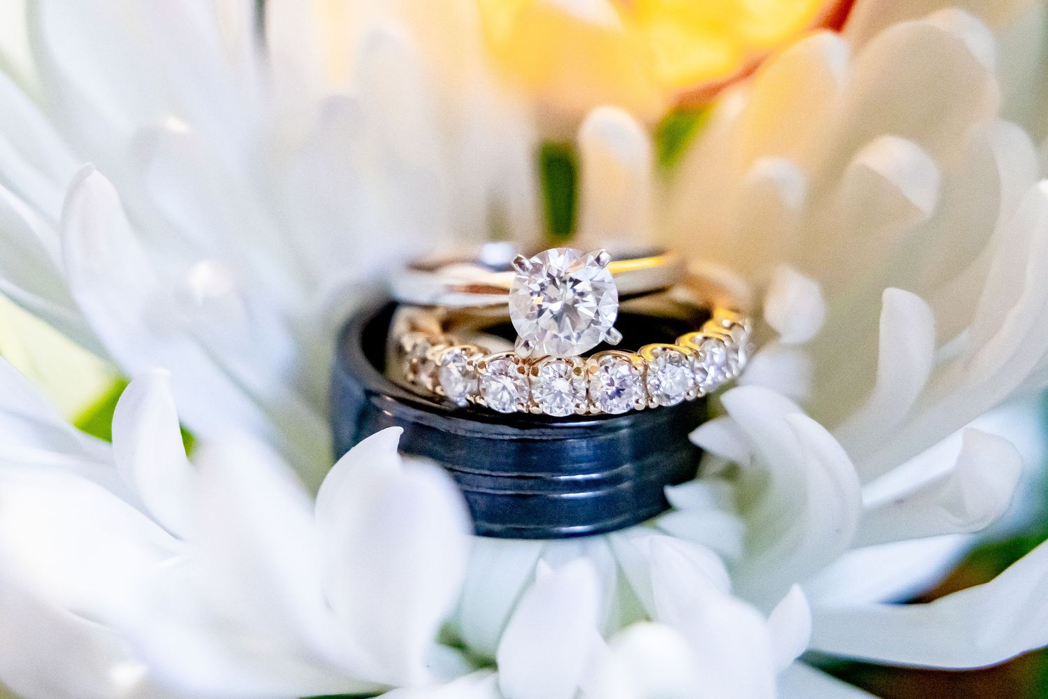 Diamond engagement ring sparkles elegantly against white flower petals in a romantic macro shot.