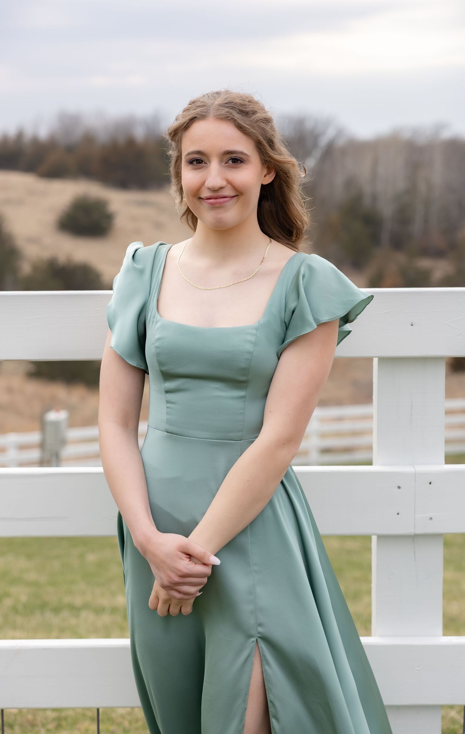 A series of outdoor portraits showing someone in a sage green dress posing by a white fence.