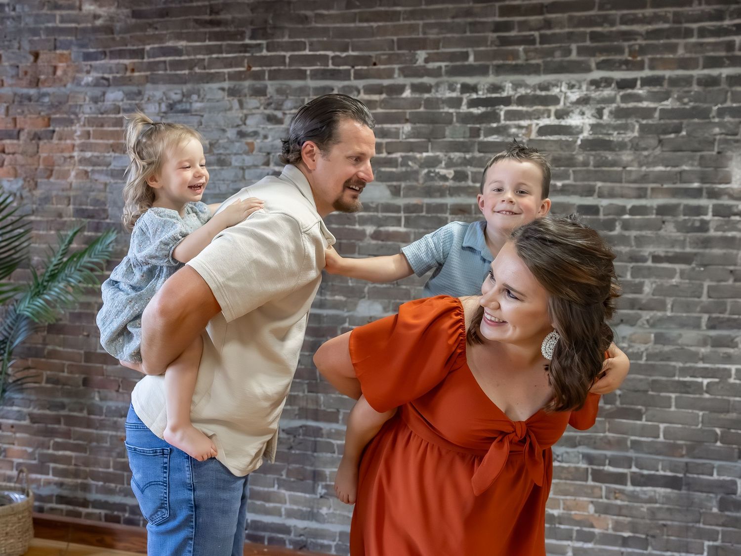 Dynamic family poses against exposed brick wall showing natural interactions.