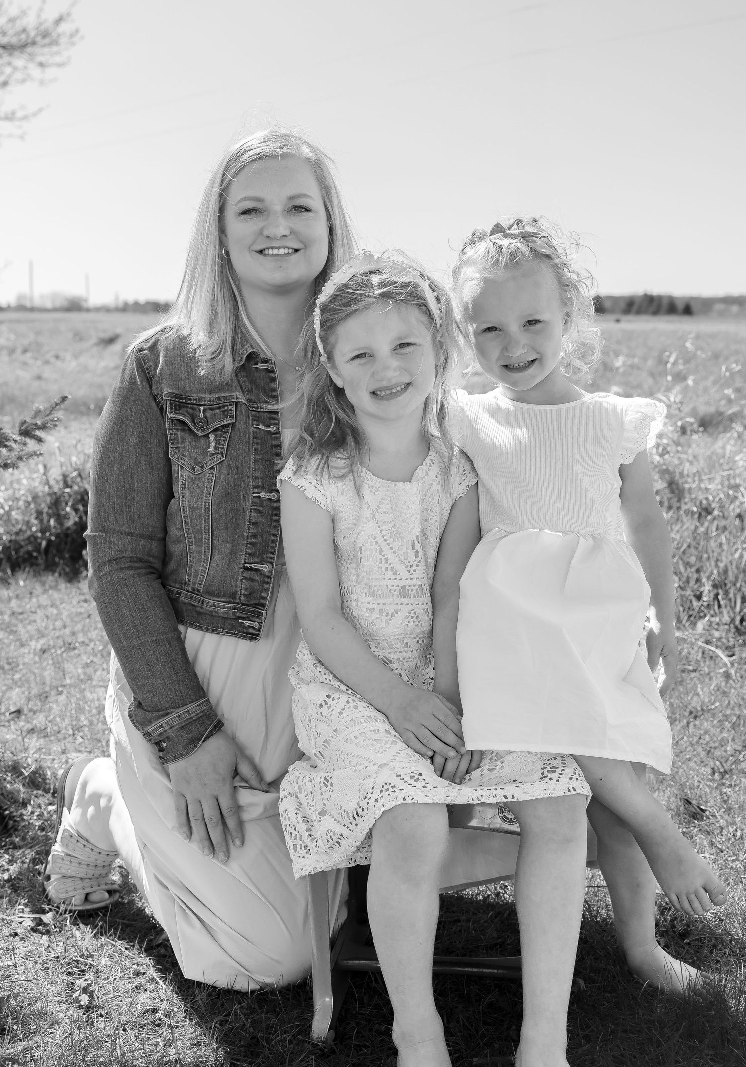 Black and white family portrait in a natural field setting with matching outfits.