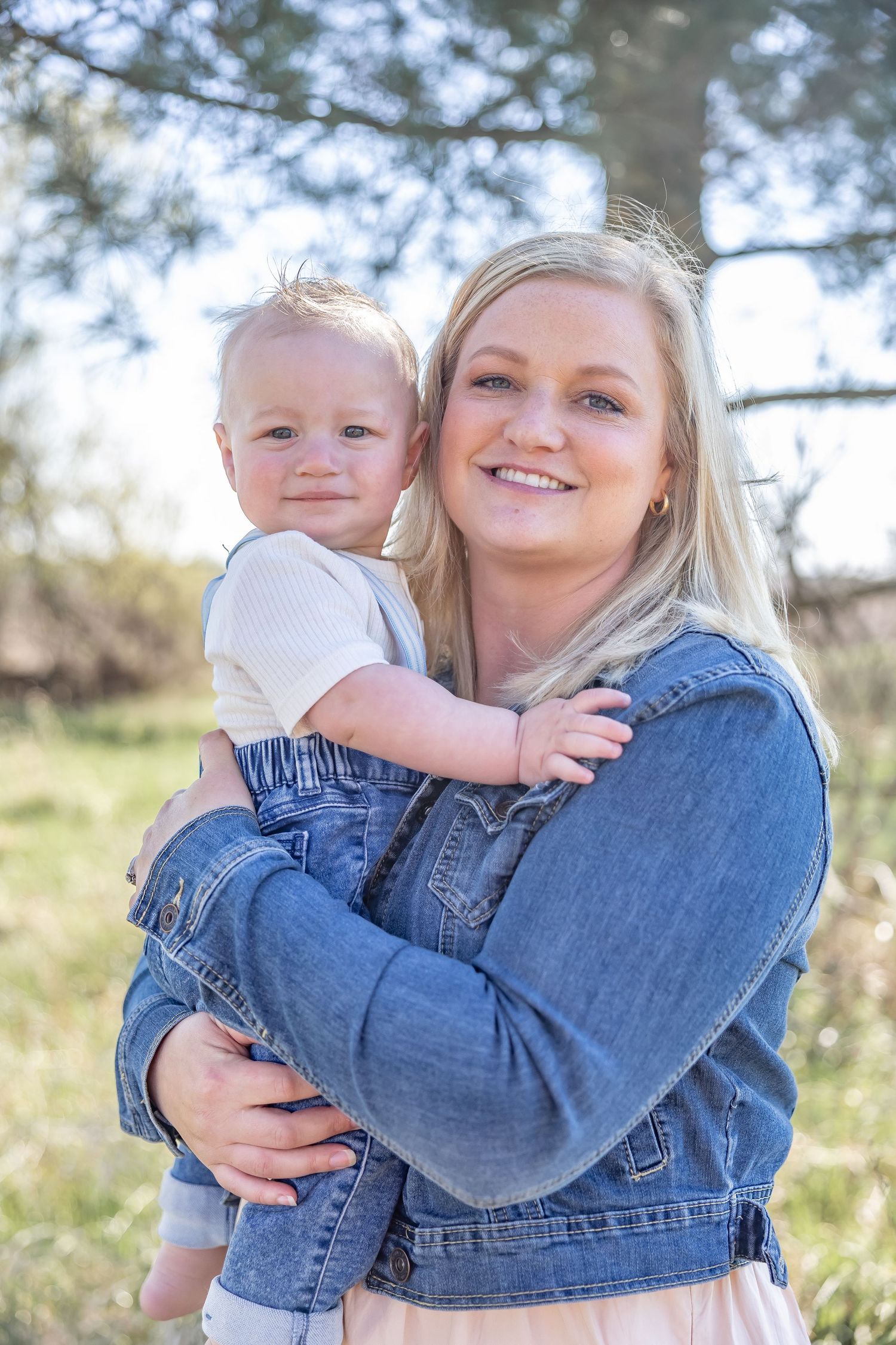 Parent in denim jacket embracing young child in casual outdoor photo series.