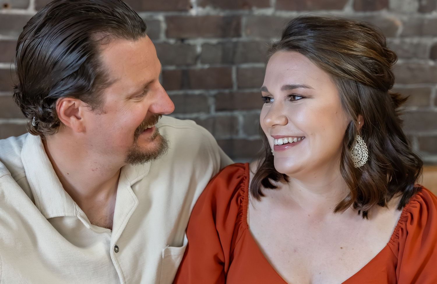 Couple sharing intimate laughs while seated together on couch.