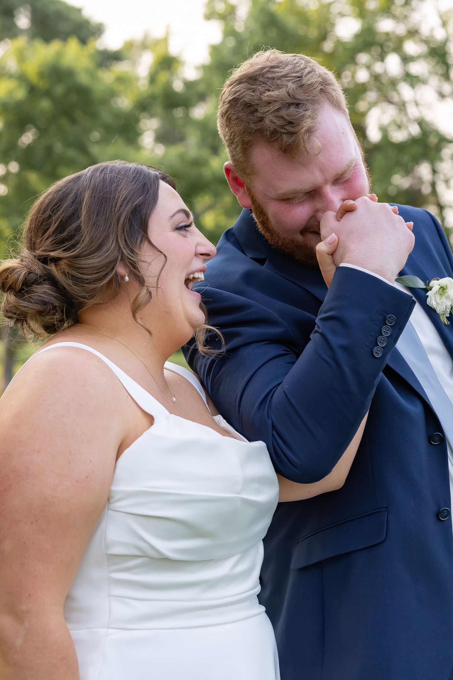 A joyful candid moment between newlyweds laughing together outdoors during their wedding photoshoot.