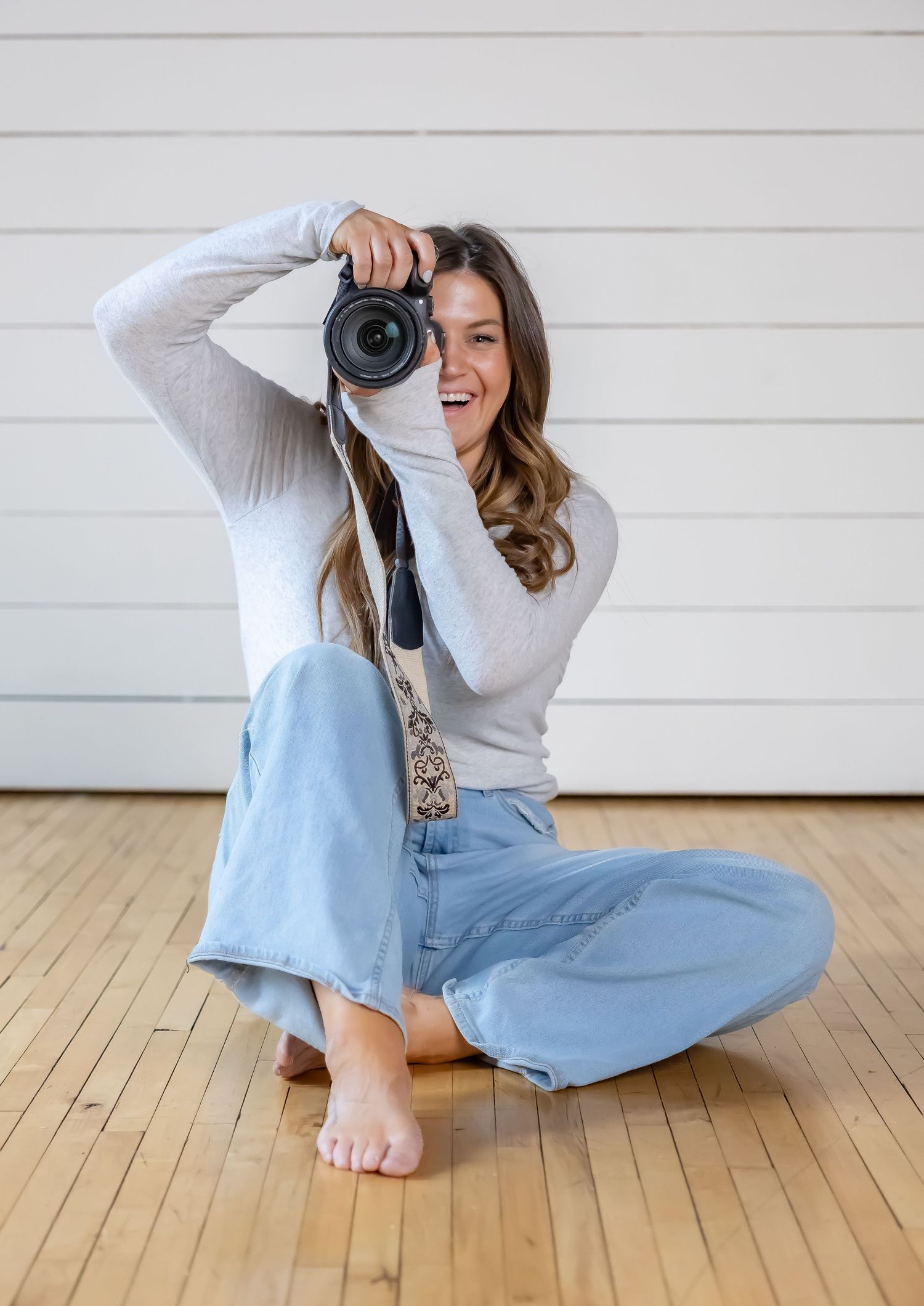 Casual lifestyle photos of a photographer lying on wooden floors with a camera.