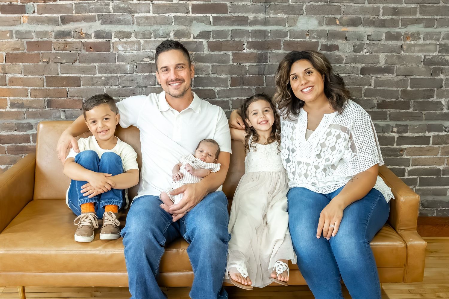Relaxed family portrait session against industrial brick wall backdrop.