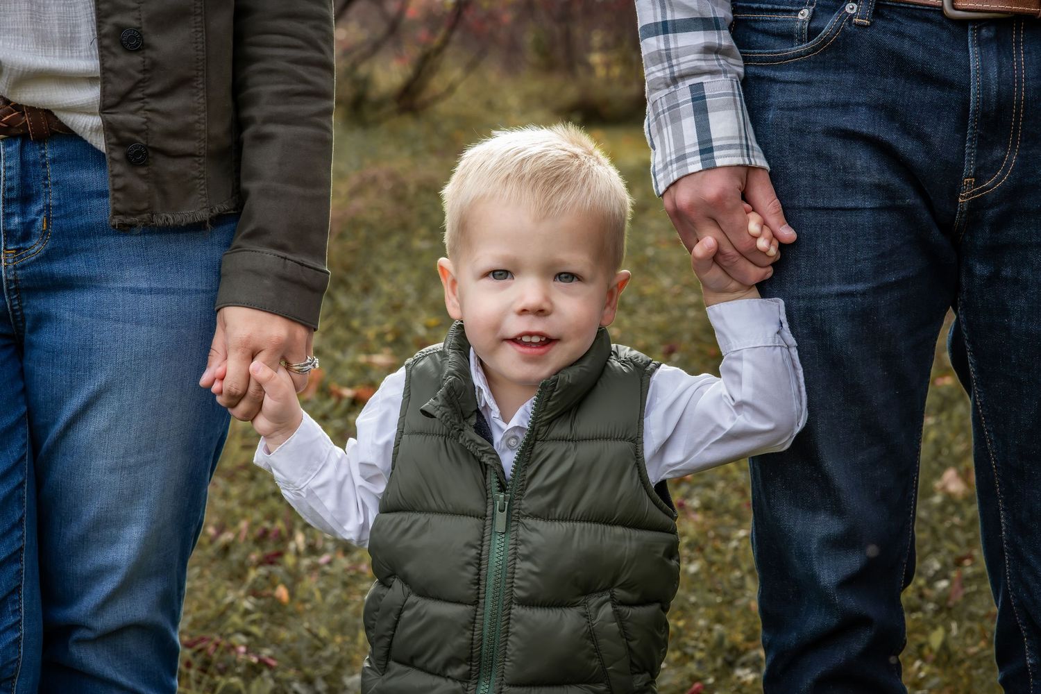 Family members standing together in casual attire against natural outdoor background.