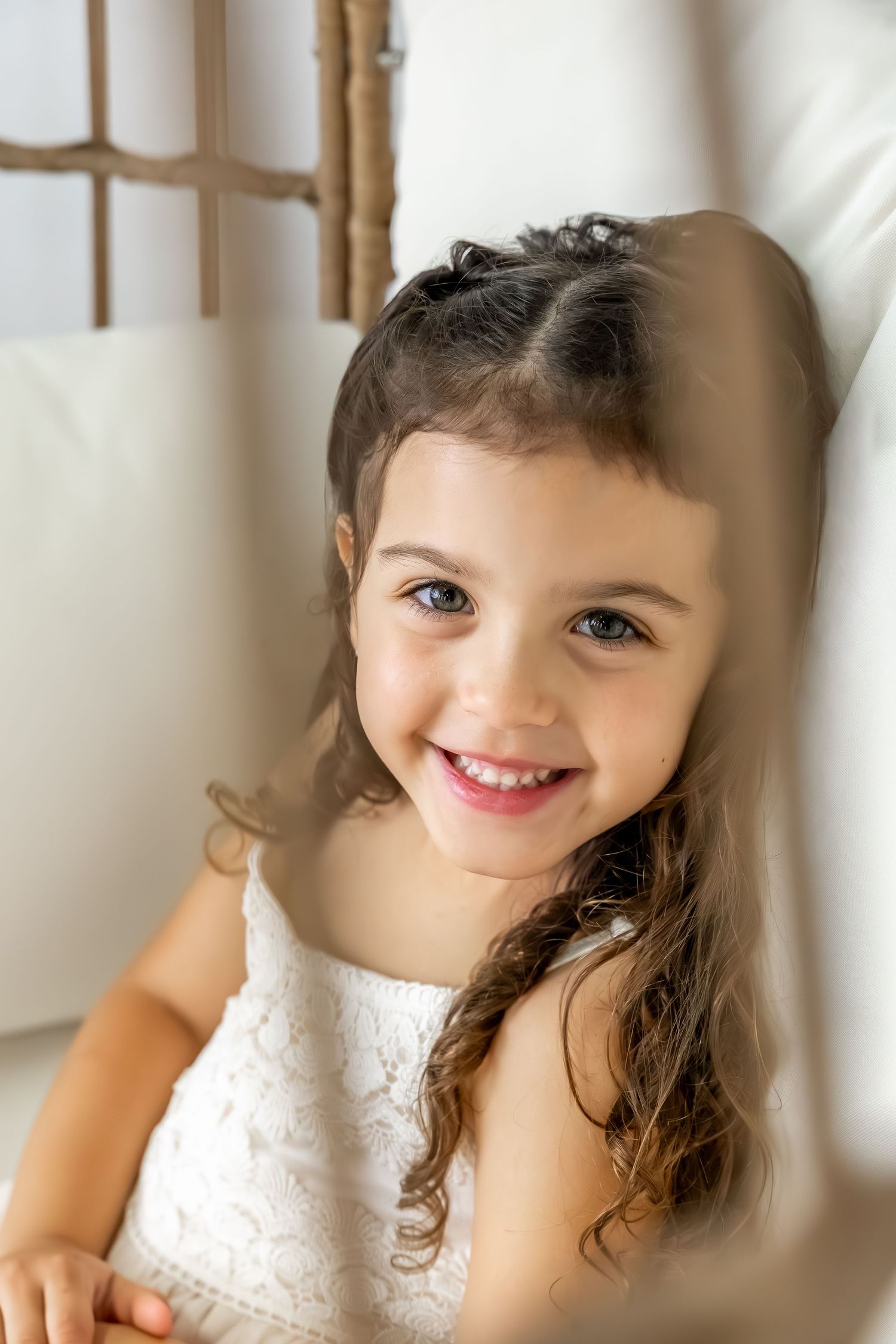 Close up view through wooden slats showing a child in a white lace dress.