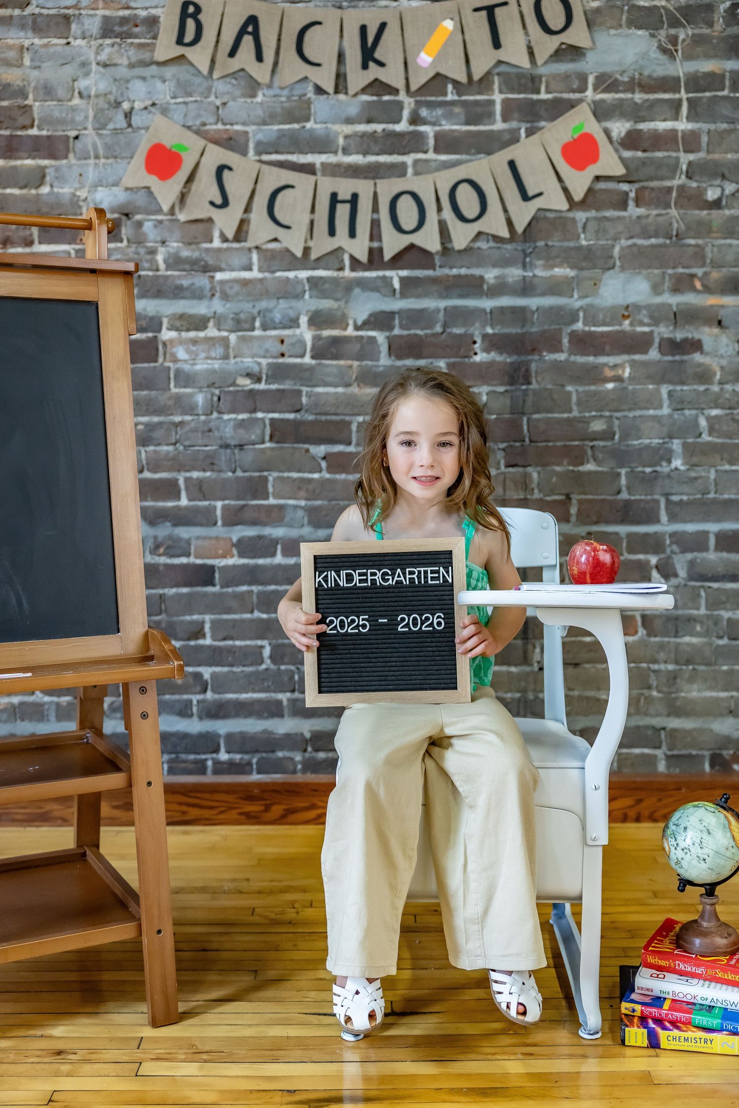 Back to school photo setup with chalkboard sign, desk, and festive banner decorations.