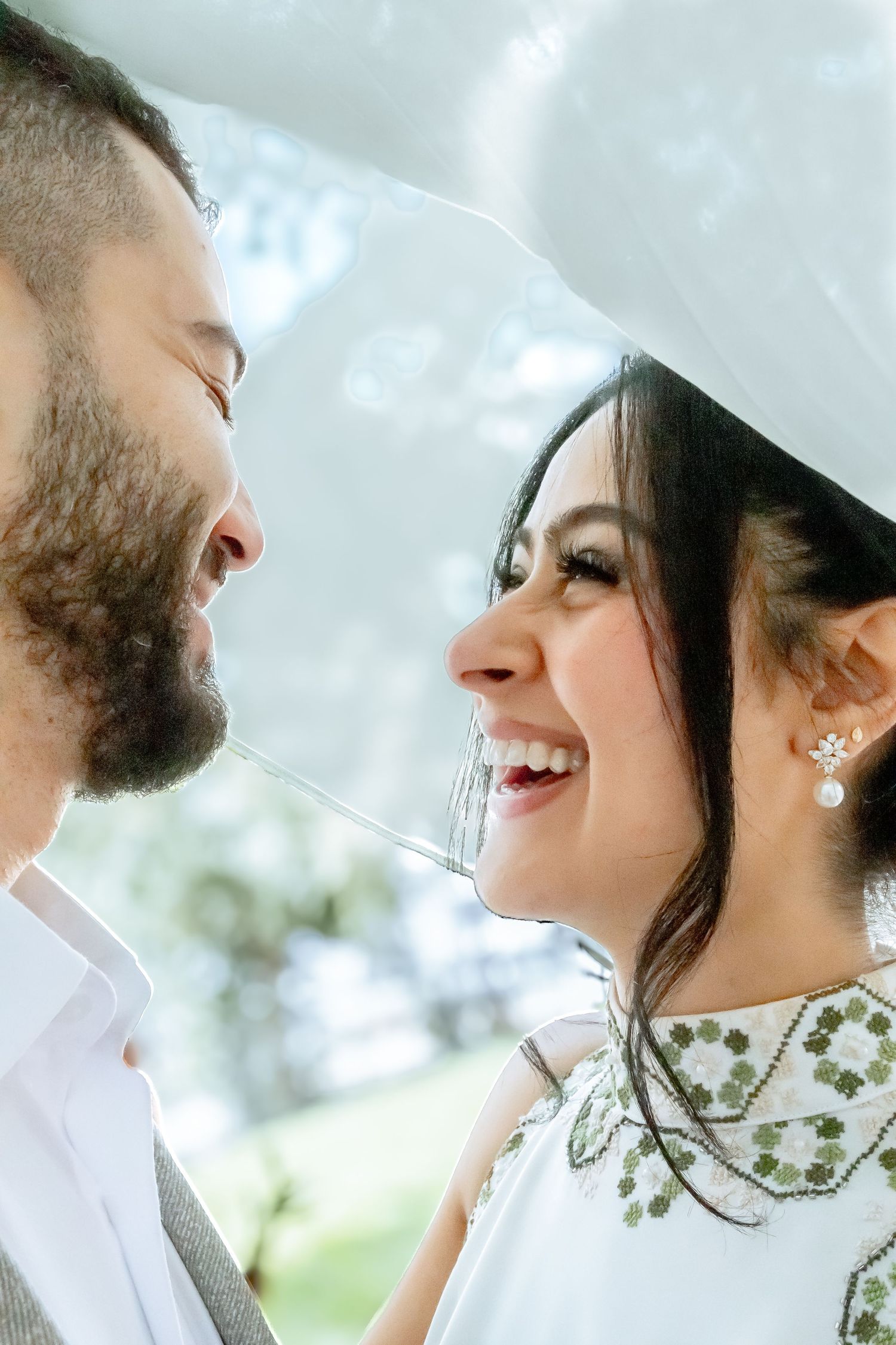 A romantic wedding portrait shows a couple sharing a joyful moment together in soft natural lighting.