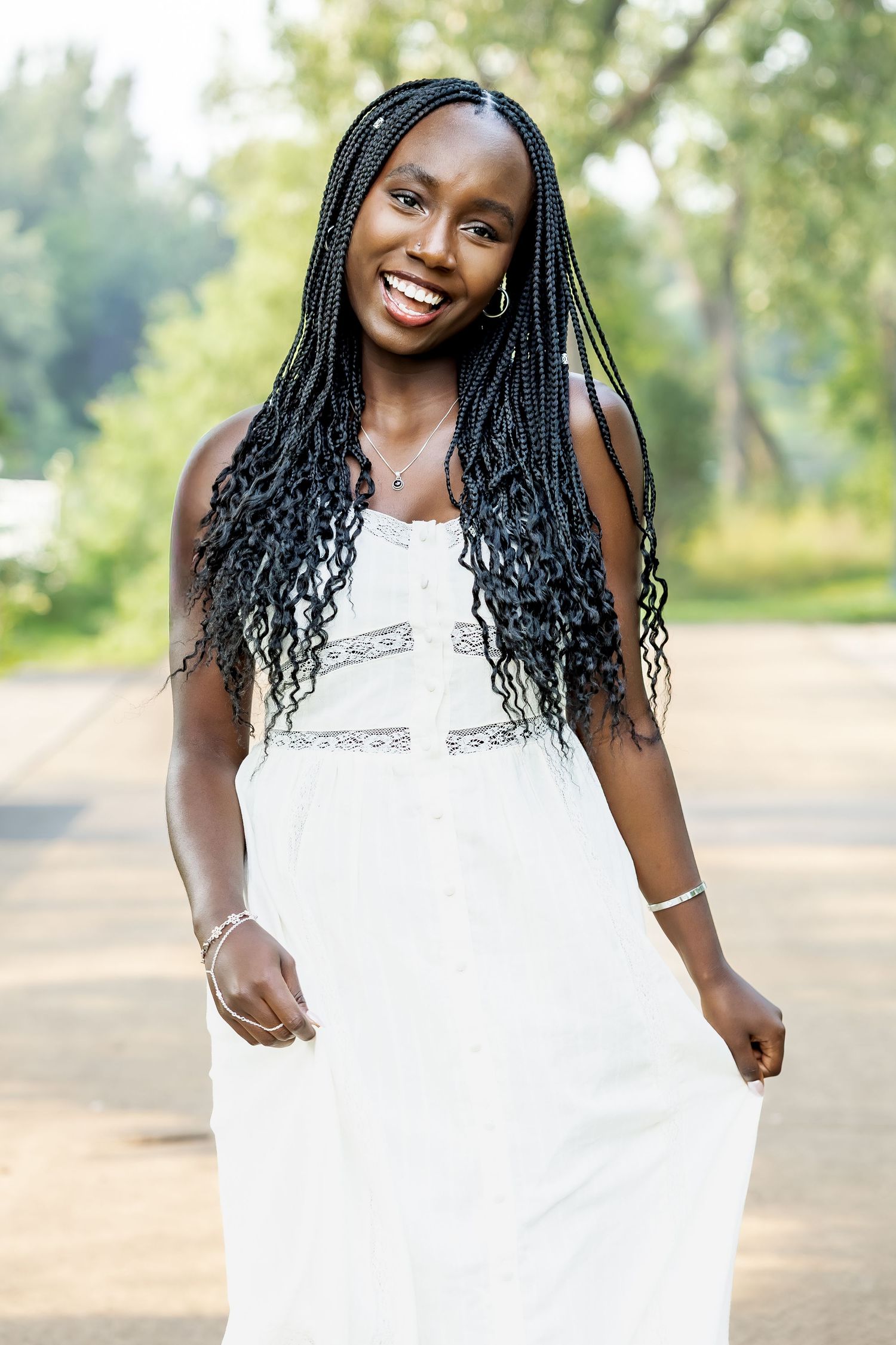 A person in a white dress poses playfully outdoors during a summer photo shoot.