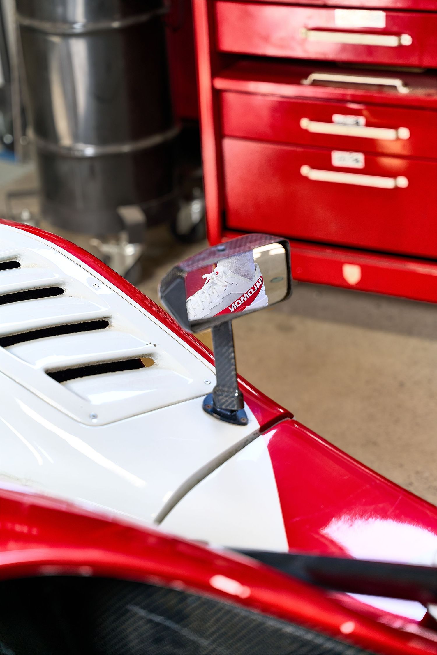 A reflection of a man perches on a racing car, showcasing the thrill and adrenaline associated with motorsport competition.