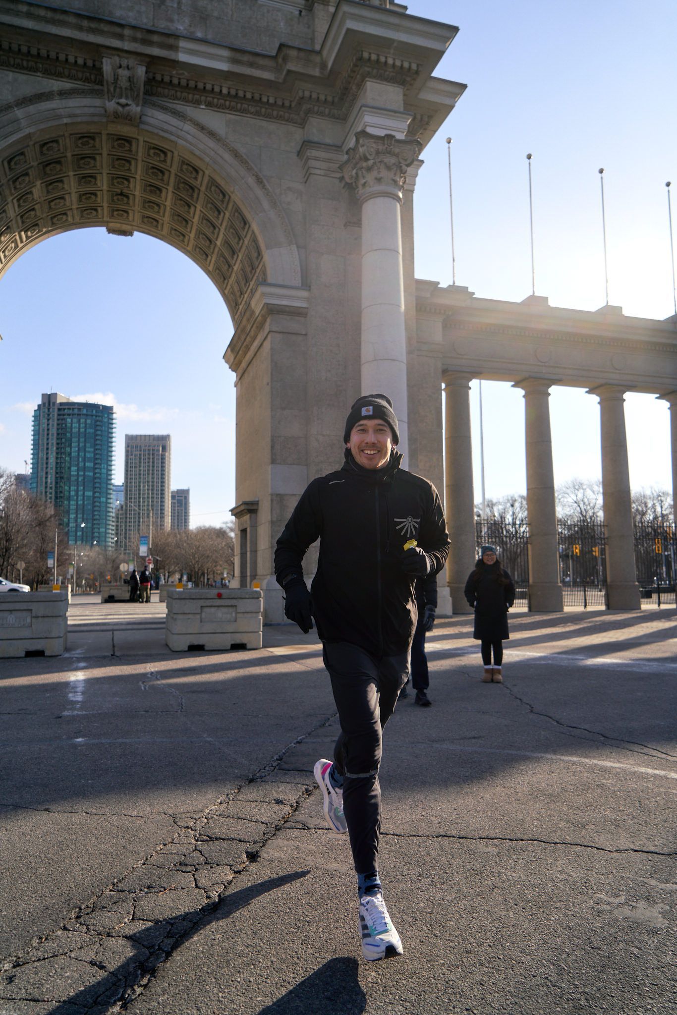 A man jogs on the sidewalk, her shadow stretching out behind her on the ground.