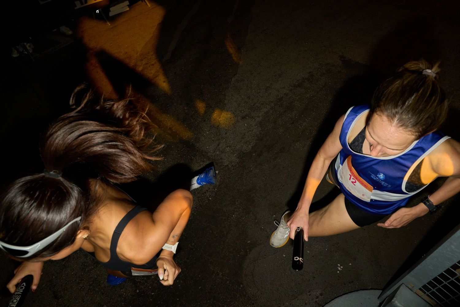 Two women jogging in a dimly lit area at night, with shadows surrounding her.