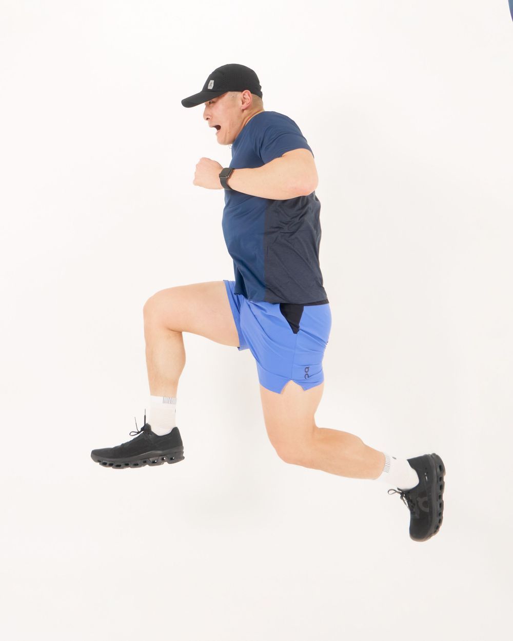 A woman in a blue shorts and black pants stands, exuding a warm and approachable vibe jumping,