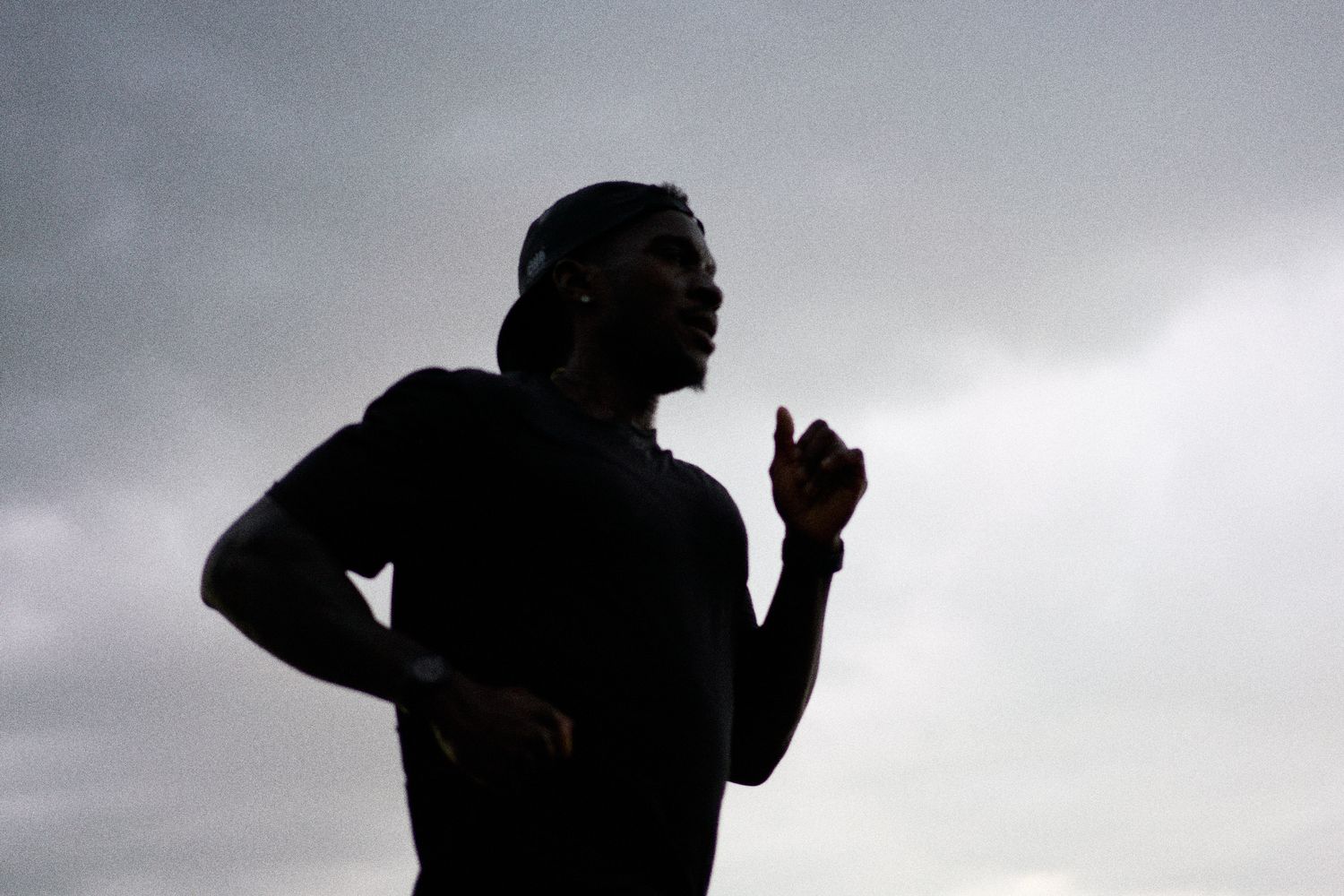 A runner silhouette stands in front of a white wall, highlighting the contrast between the figure and the light background.