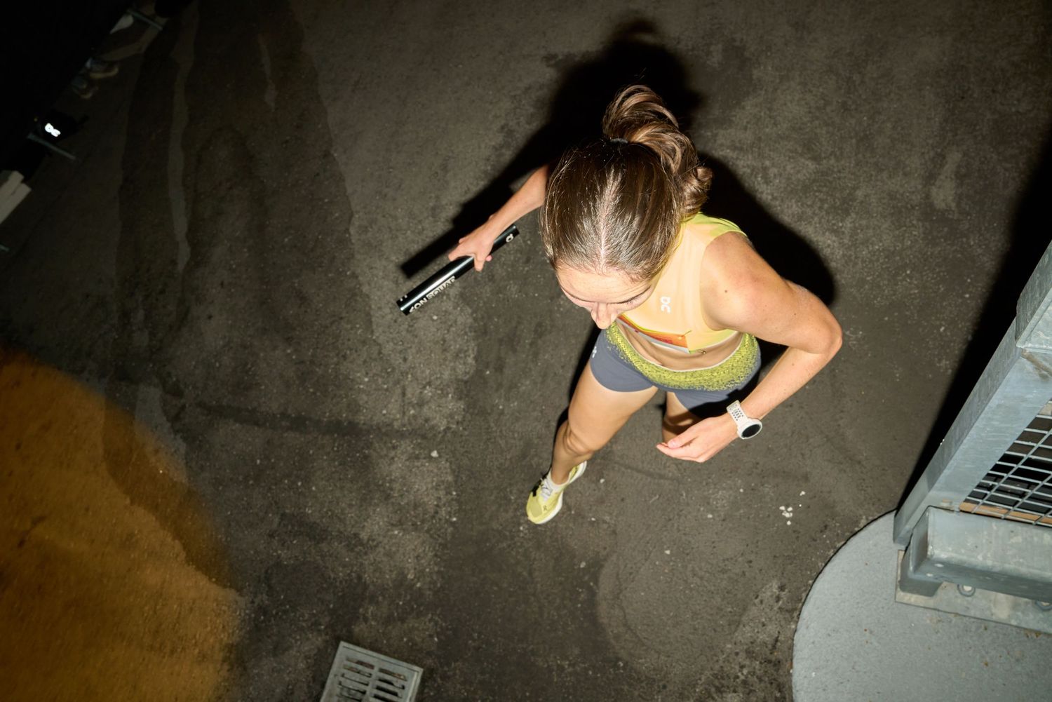 A woman sprinting through a darkened street at night, with minimal light visible.