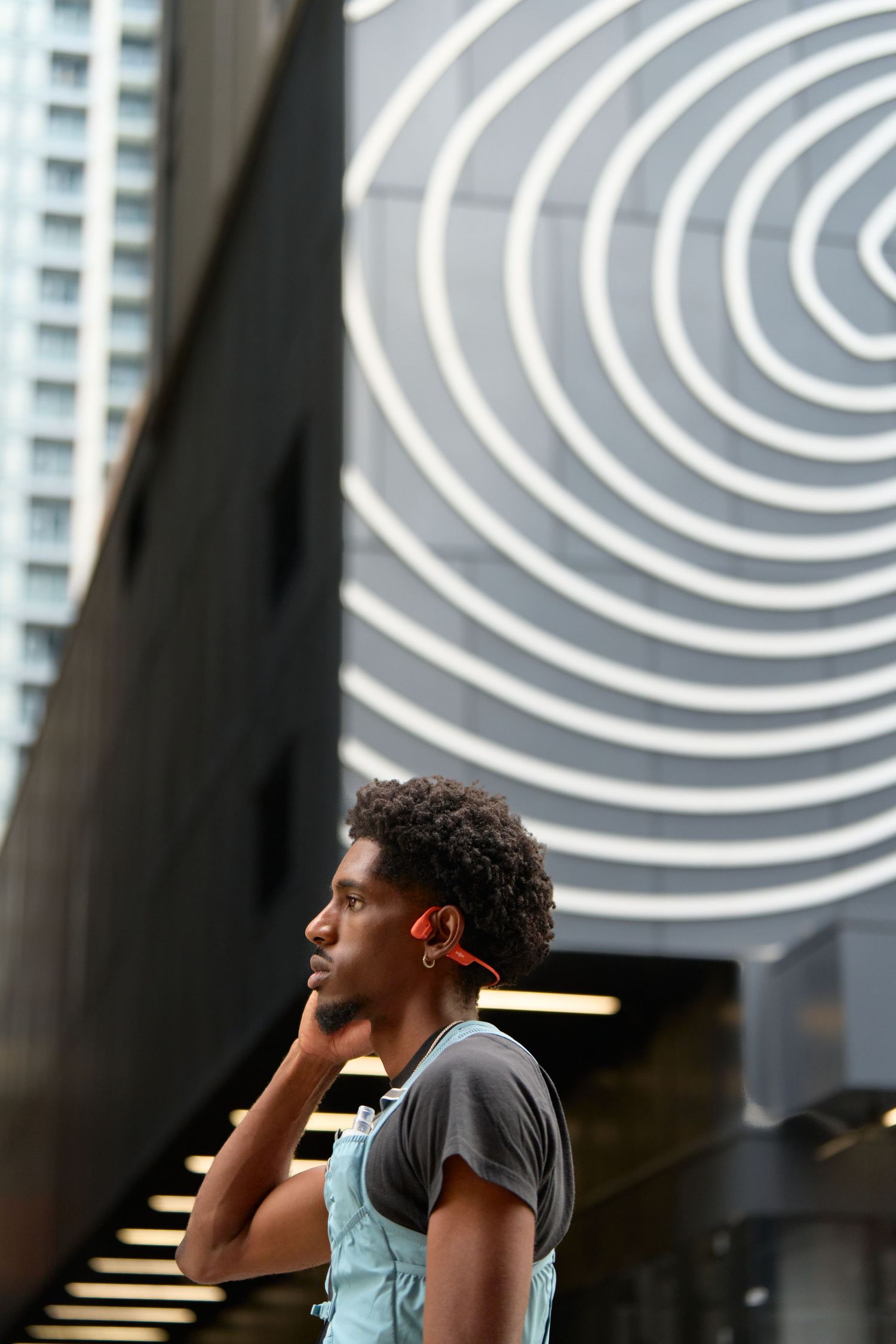 A man wearing a orange headphones and running vest looking focused and attentive.