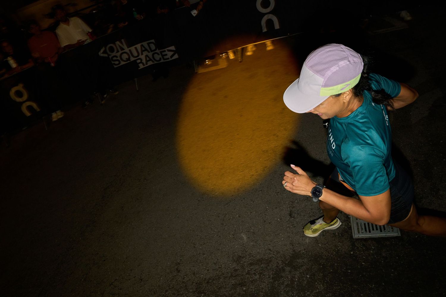 A woman running swiftly in the dark of night, illuminated by faint streetlights.