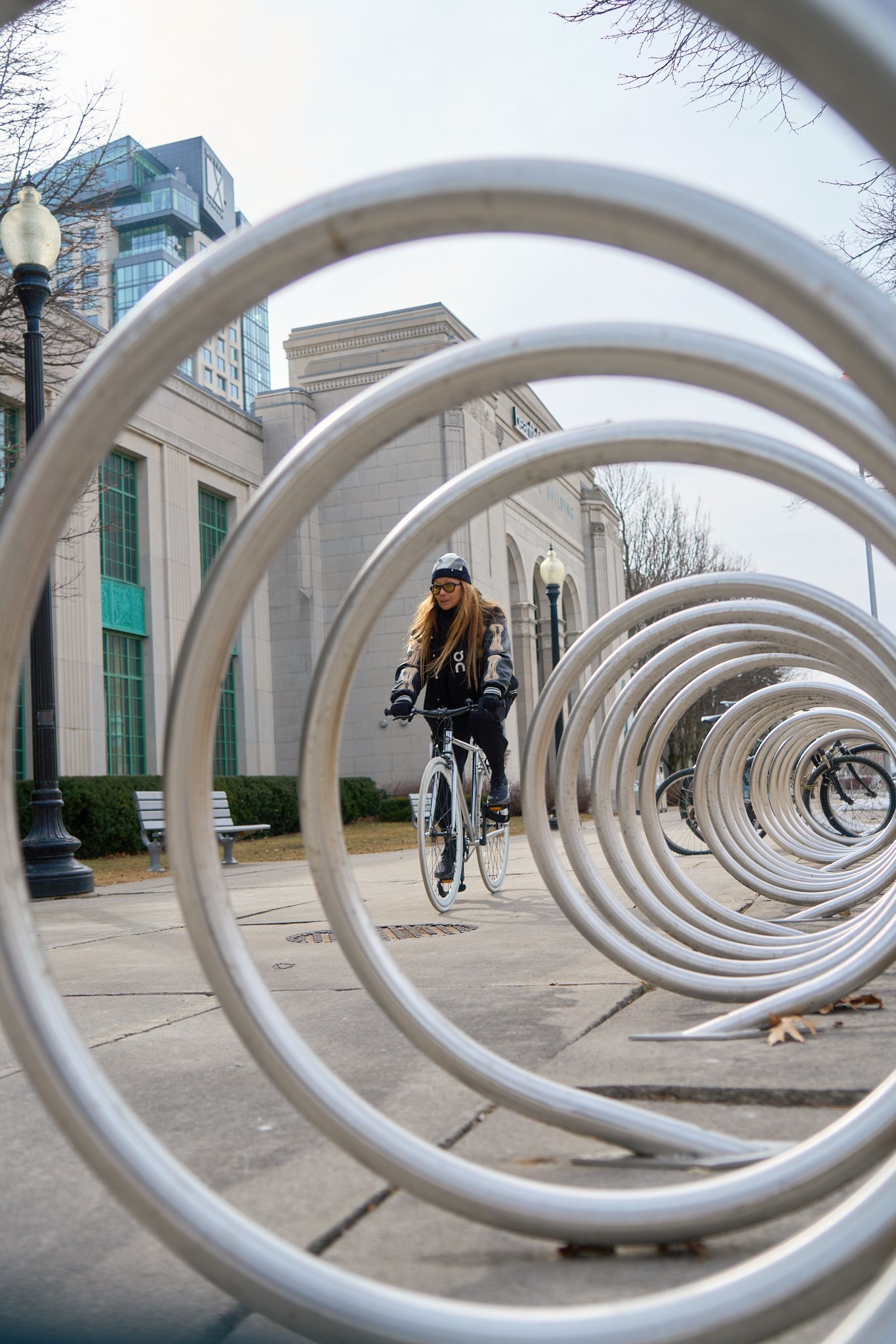 A woman cycling through a maze of shiny metal tubes, showcasing her adventurous spirit and love for outdoor activities.