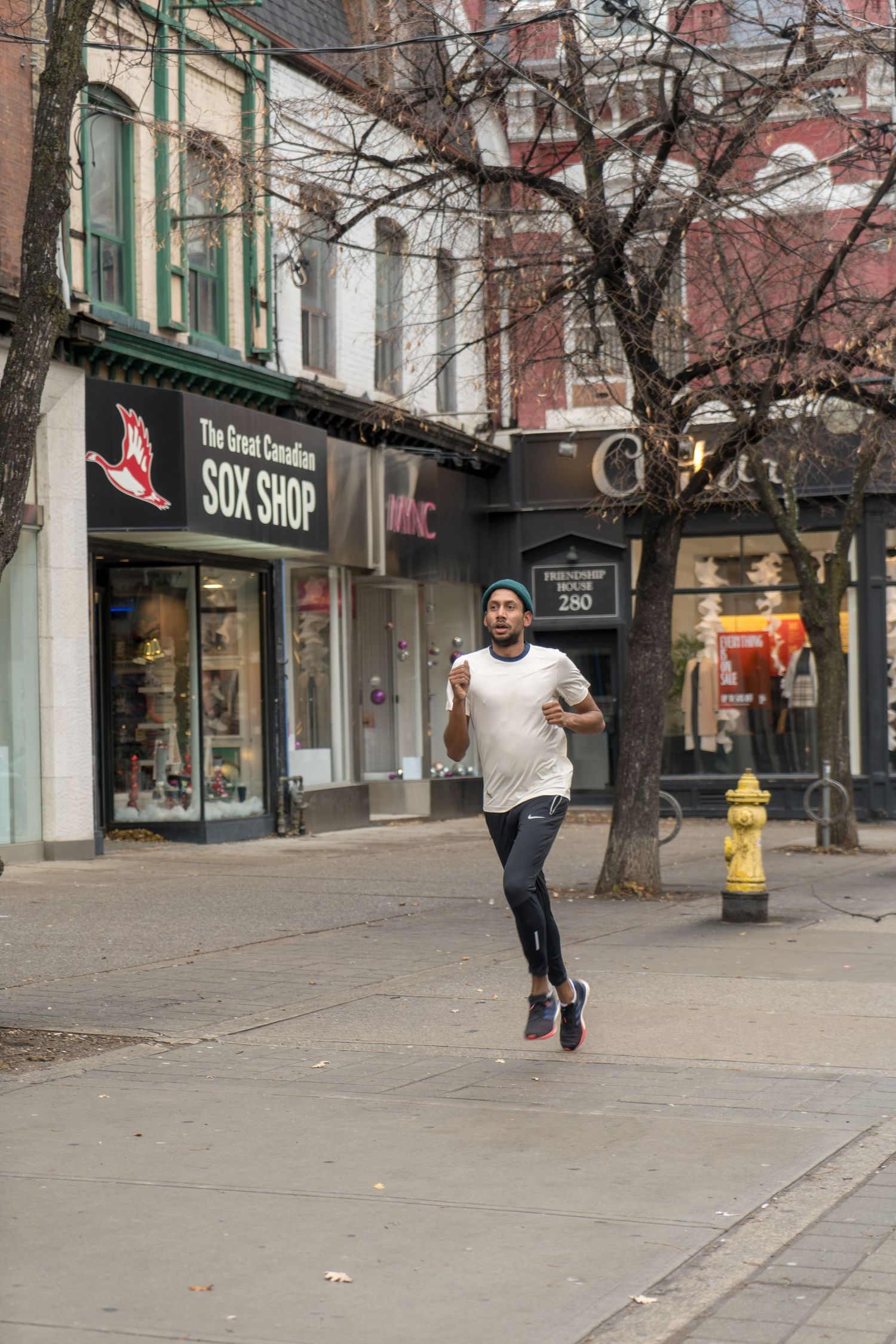 A man in a blue shirt runs in a marathon, rain pouring down around him, showcasing determination and resilience.