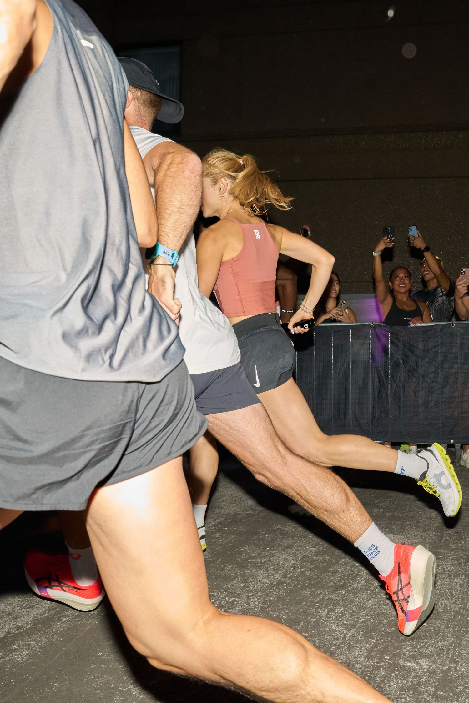 A a group of women sprinting at night, with a dark sky and minimal light from nearby sources.