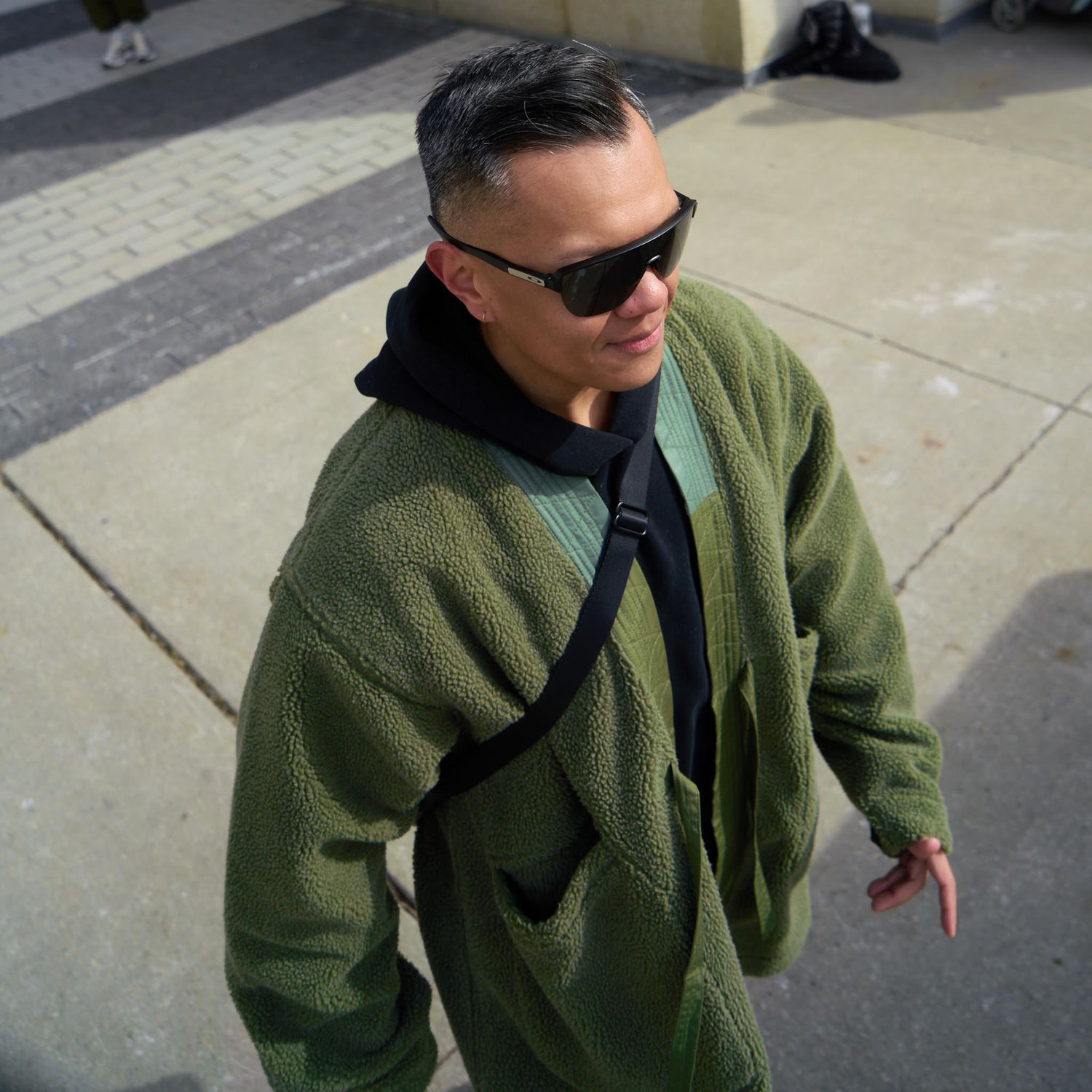A friend in sunglasses and jackets, laughing together in a bright outdoor setting.