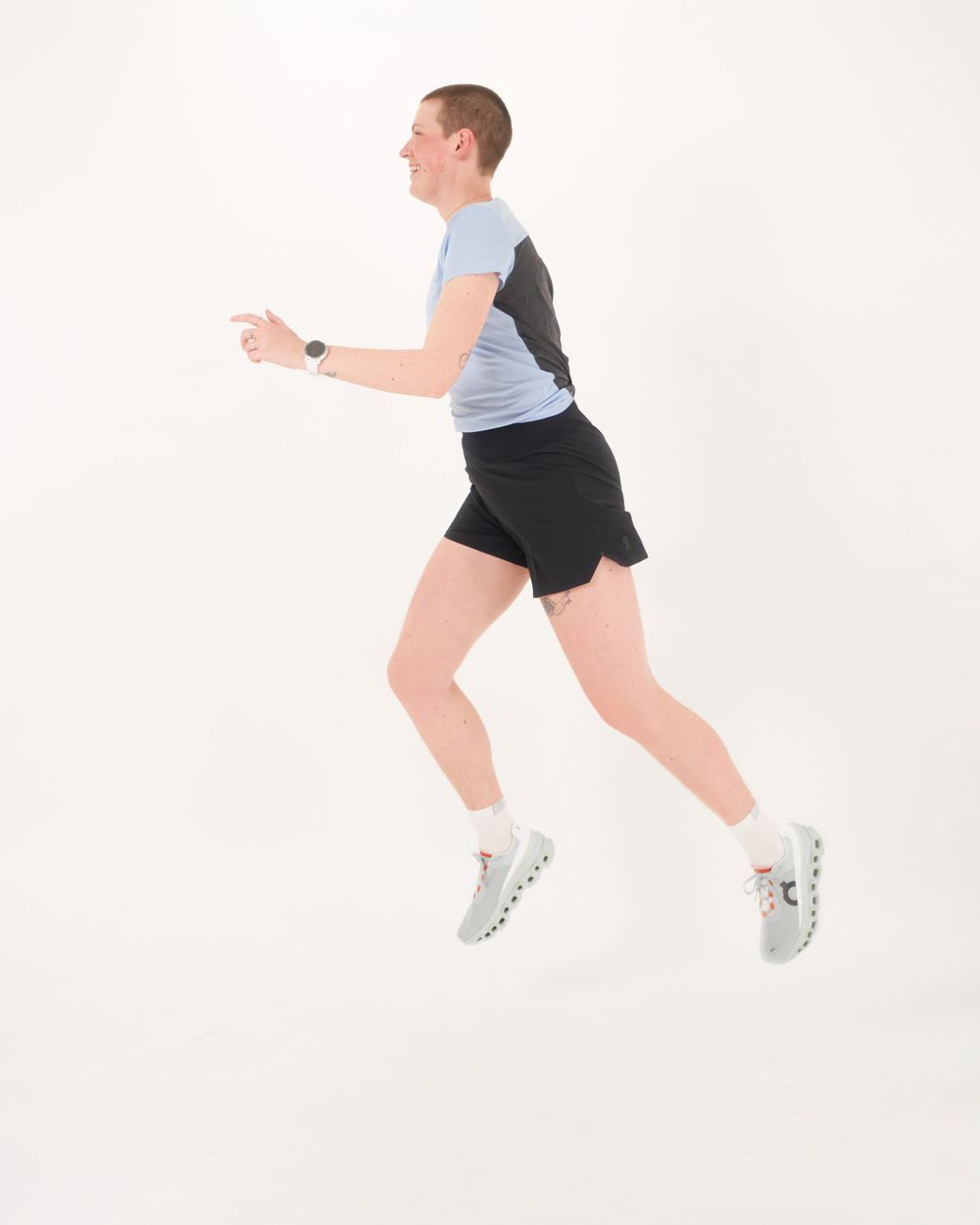 woman dressed in a blue shirt and black pants poses with a friendly smile jumping.