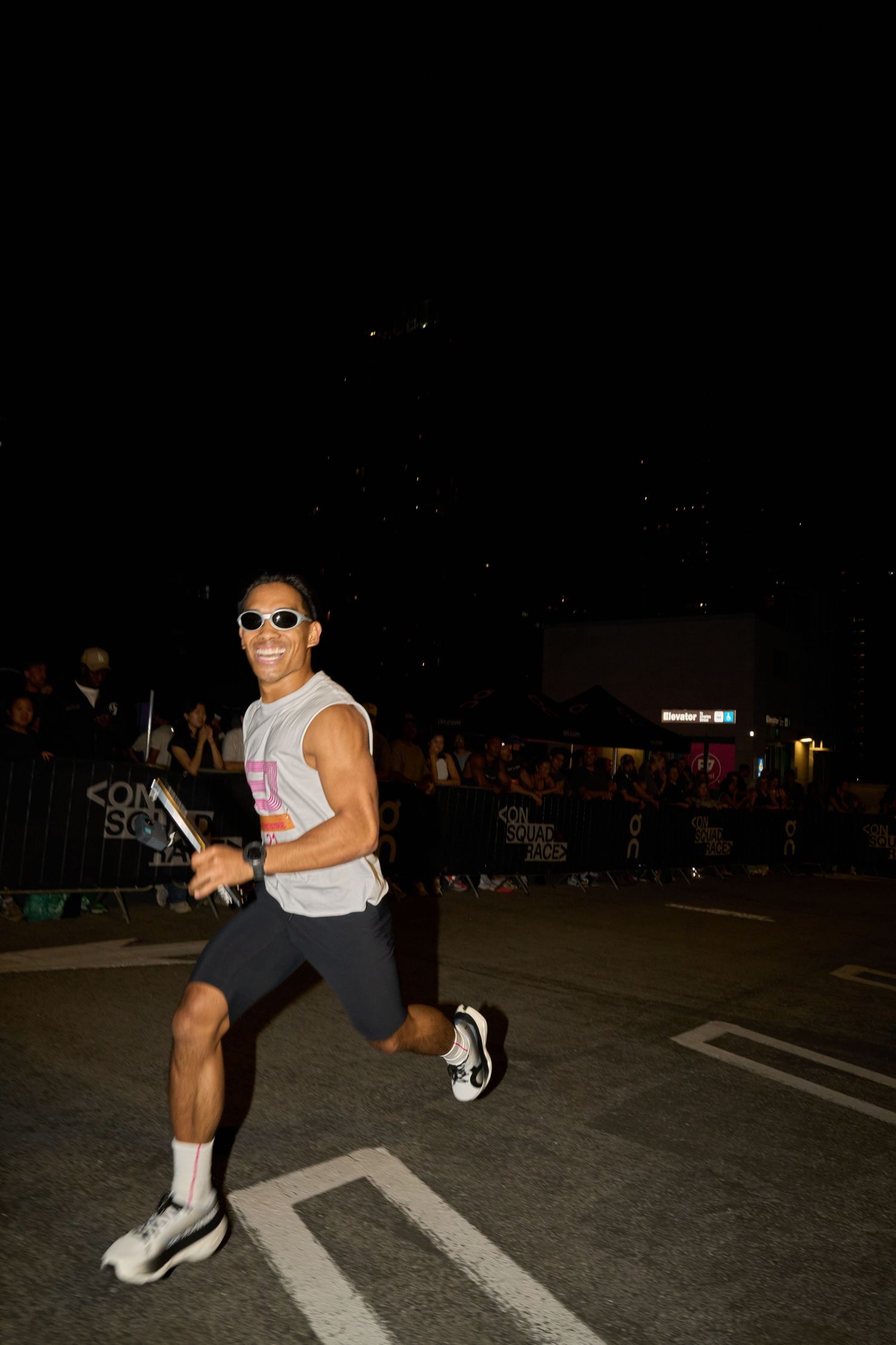 At night, a runner are positioned on a metal baton, surrounded by darkness and faint lighting.