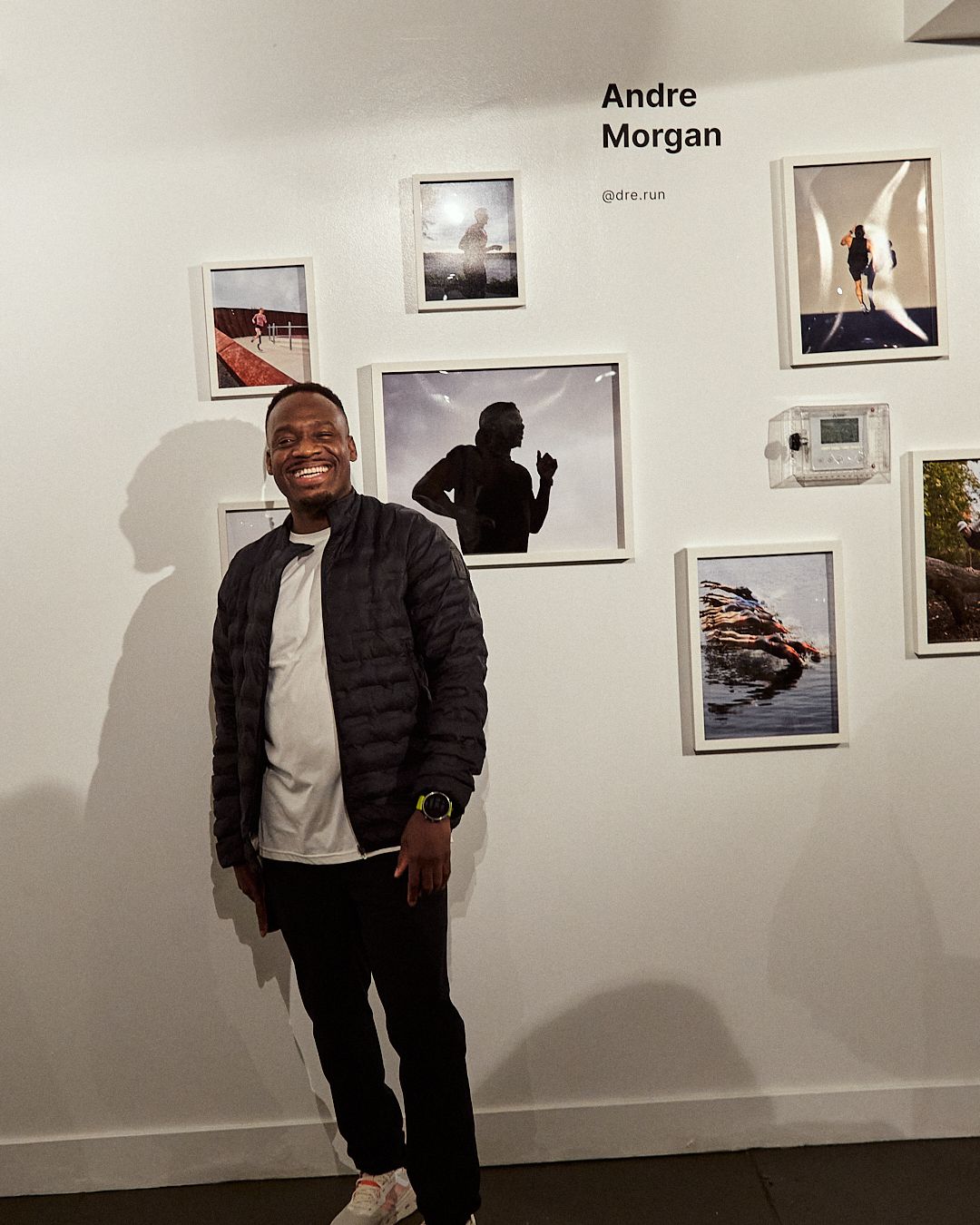 A man points at a wall filled with photographs, indicating particular images for emphasis or explanation.