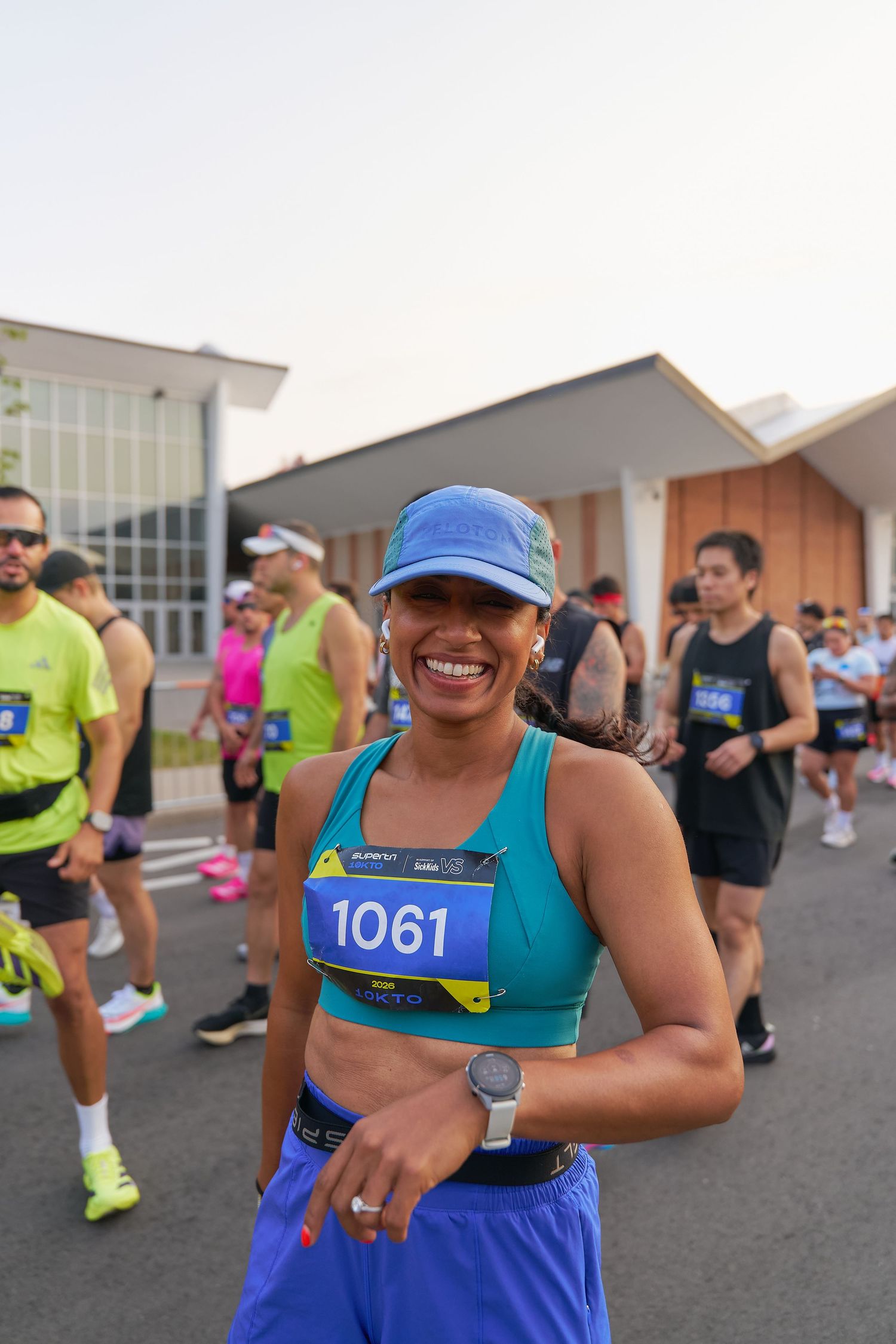 A woman wearing a blue top and shorts smiles brightly, exuding a cheerful and positive demeanor.