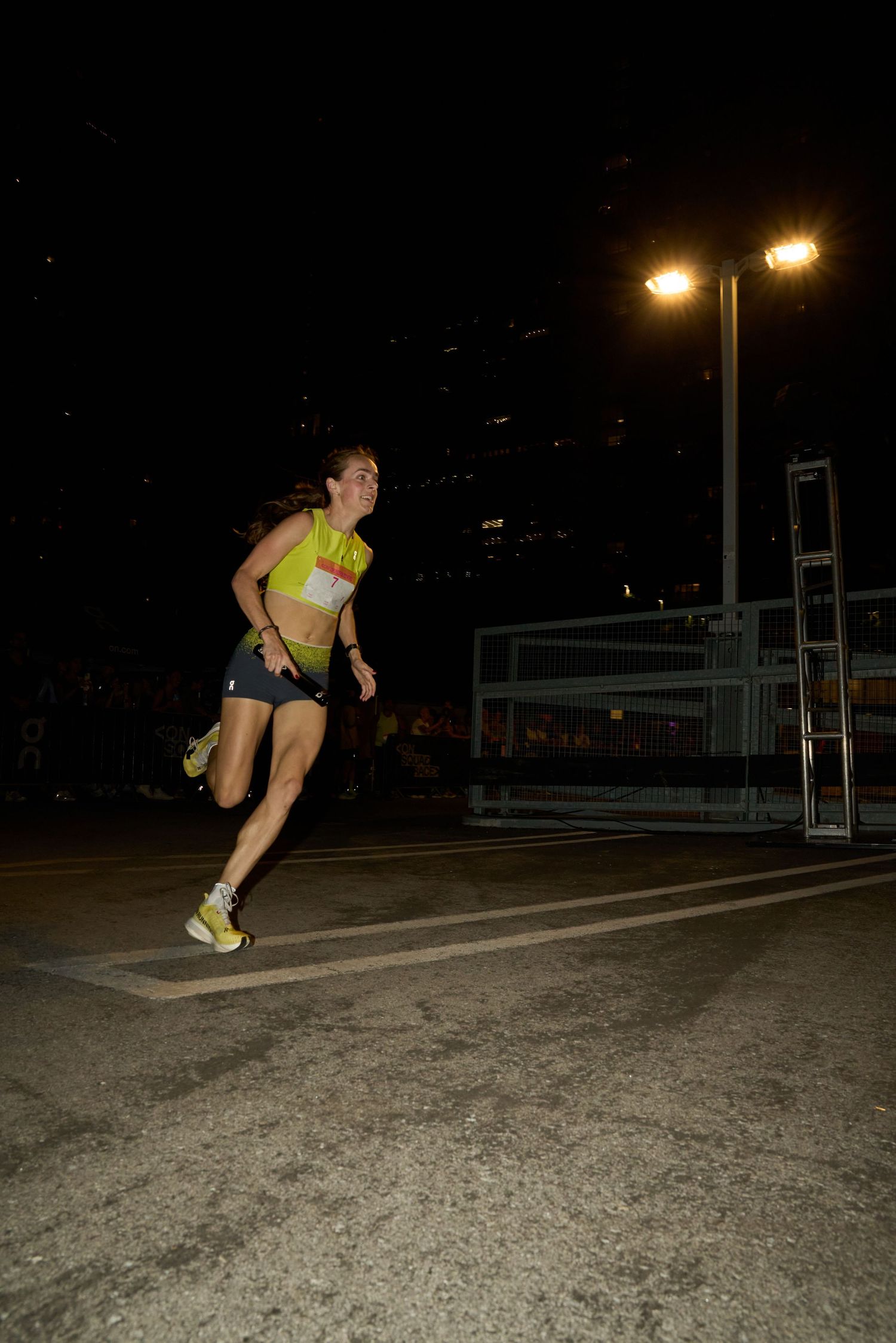 A woman running alone in the nighttime darkness, with only a hint of light nearby.