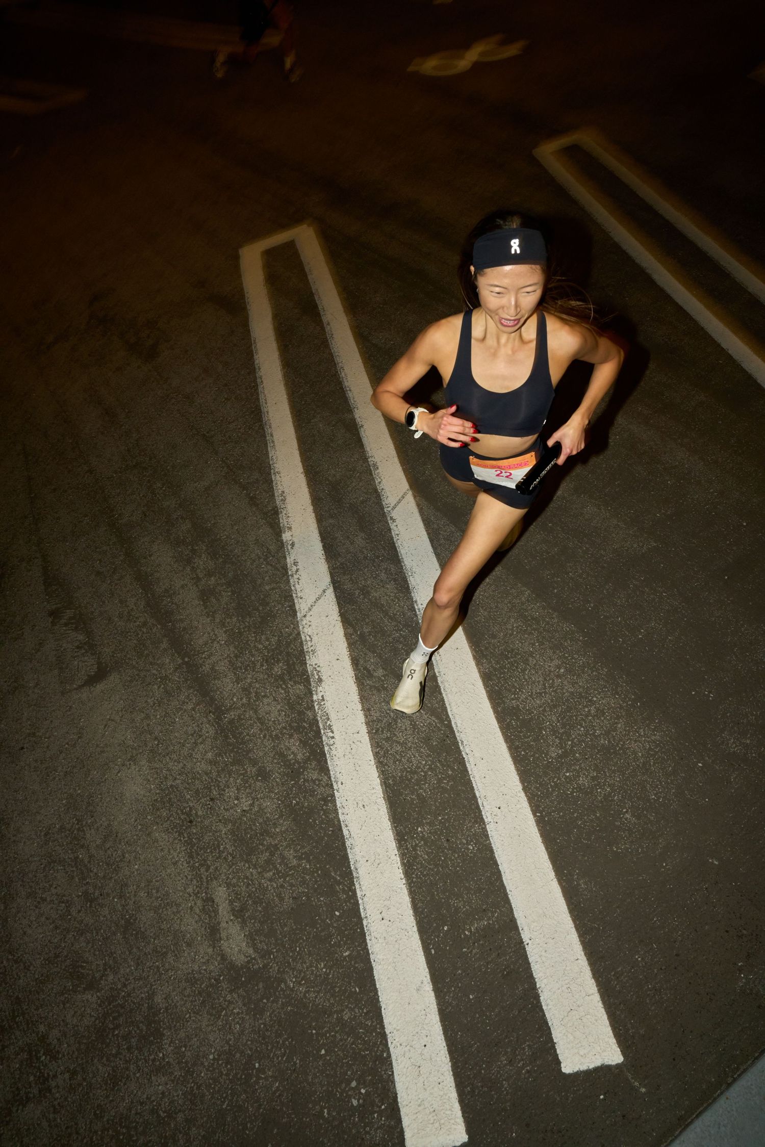 A woman in motion, running at night in a dark environment, with limited visibility.