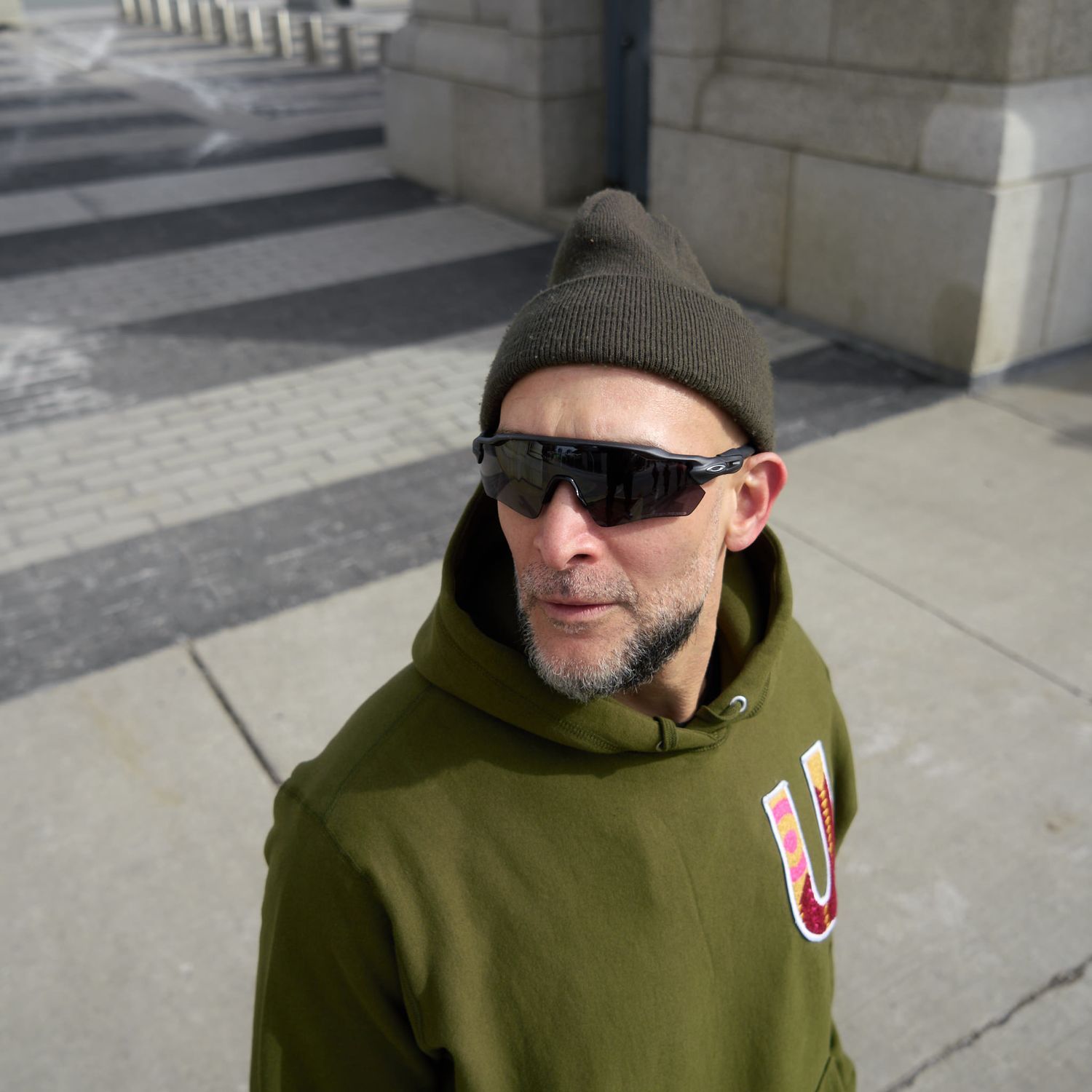 A cheerful man of people in jackets and sunglasses, gathered together in a sunny environment.