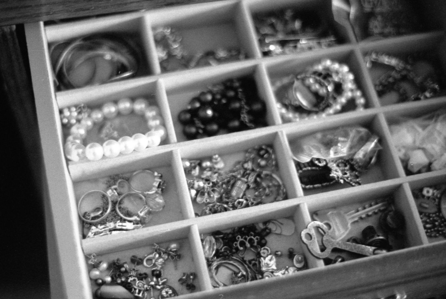 Close-up of jewelry box compartments filled with rings and necklaces.