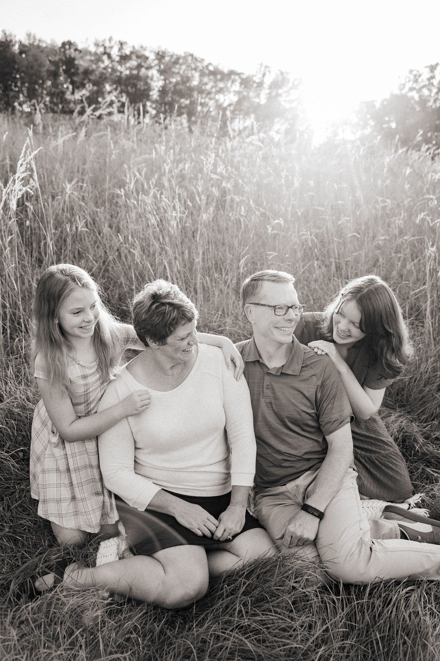 Black and white portrait session in tall grass during golden hour.