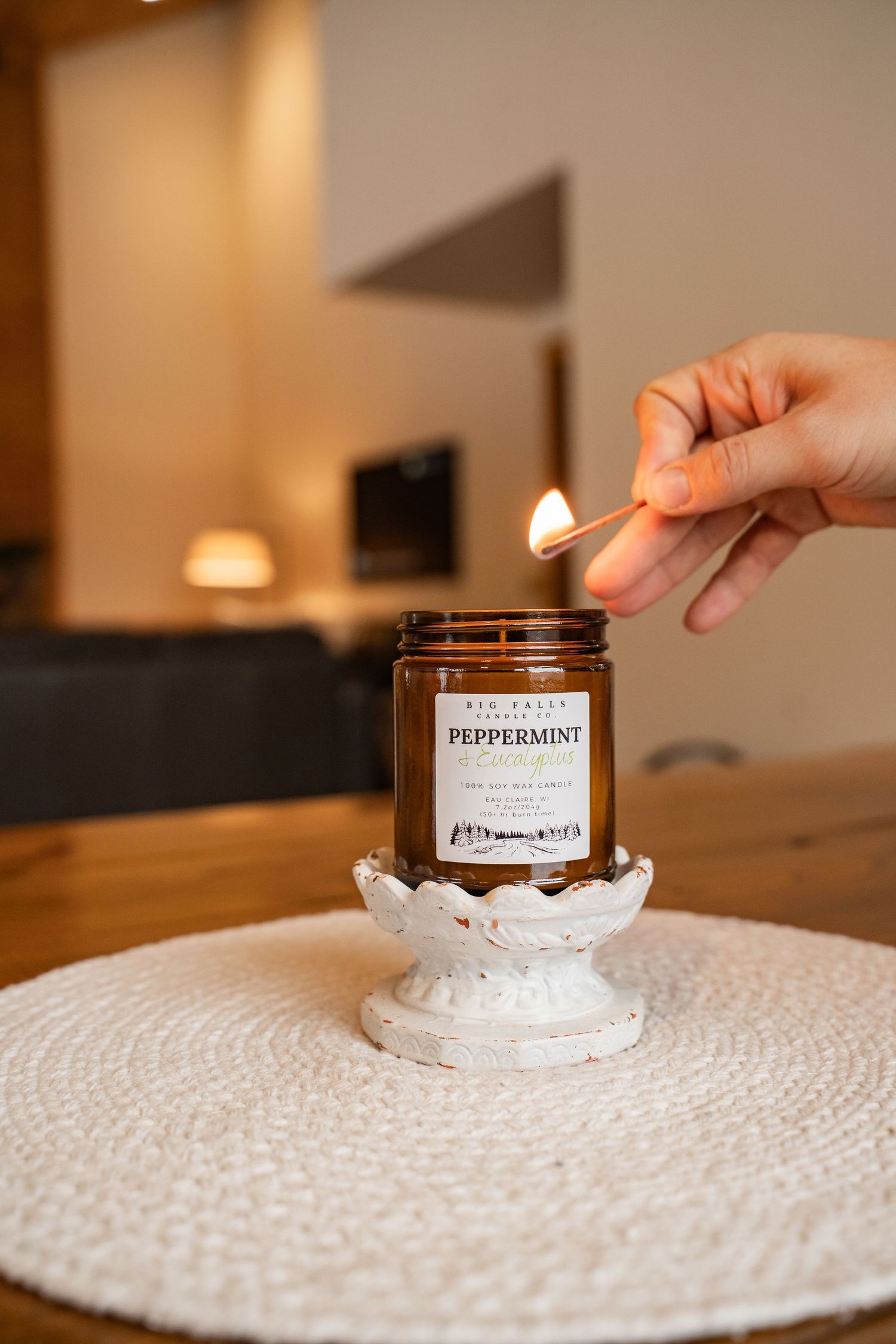 Peppermint scented candle being placed on white textured placemat.