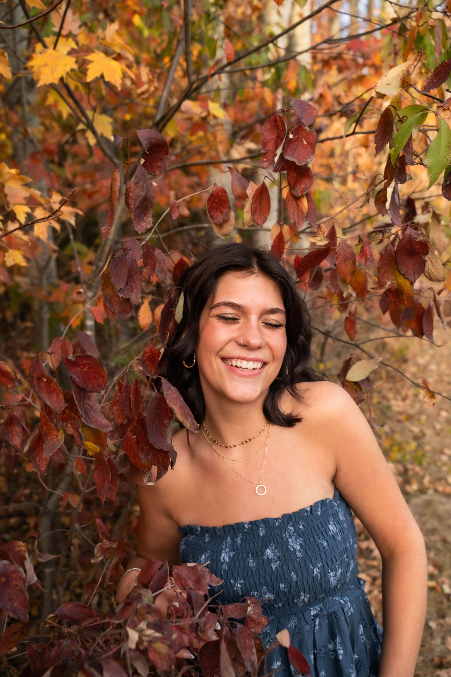 Portrait series in autumn setting with fall foliage and blue strapless dress.