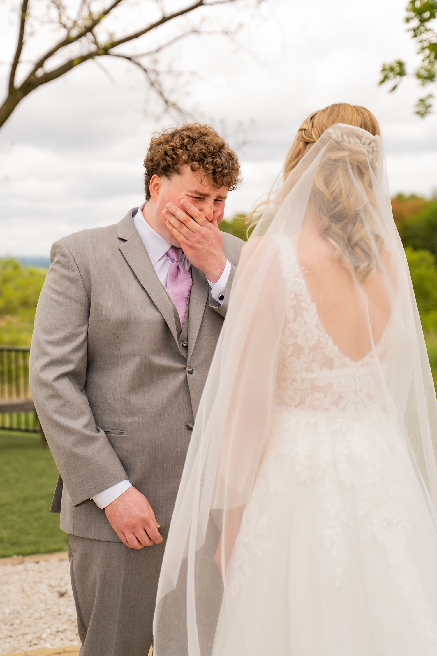 An emotional first look moment between a couple, with the groom in grey suit reacting to seeing the bride.