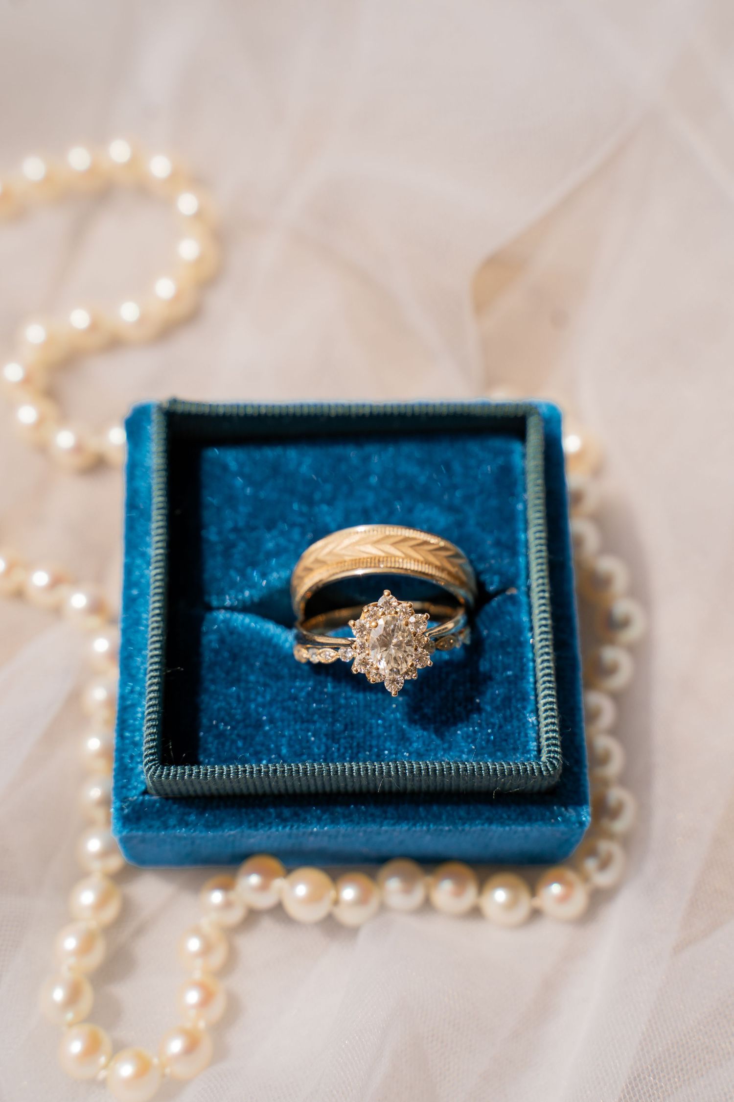 Diamond engagement ring in blue velvet box with pearl necklace decoration.