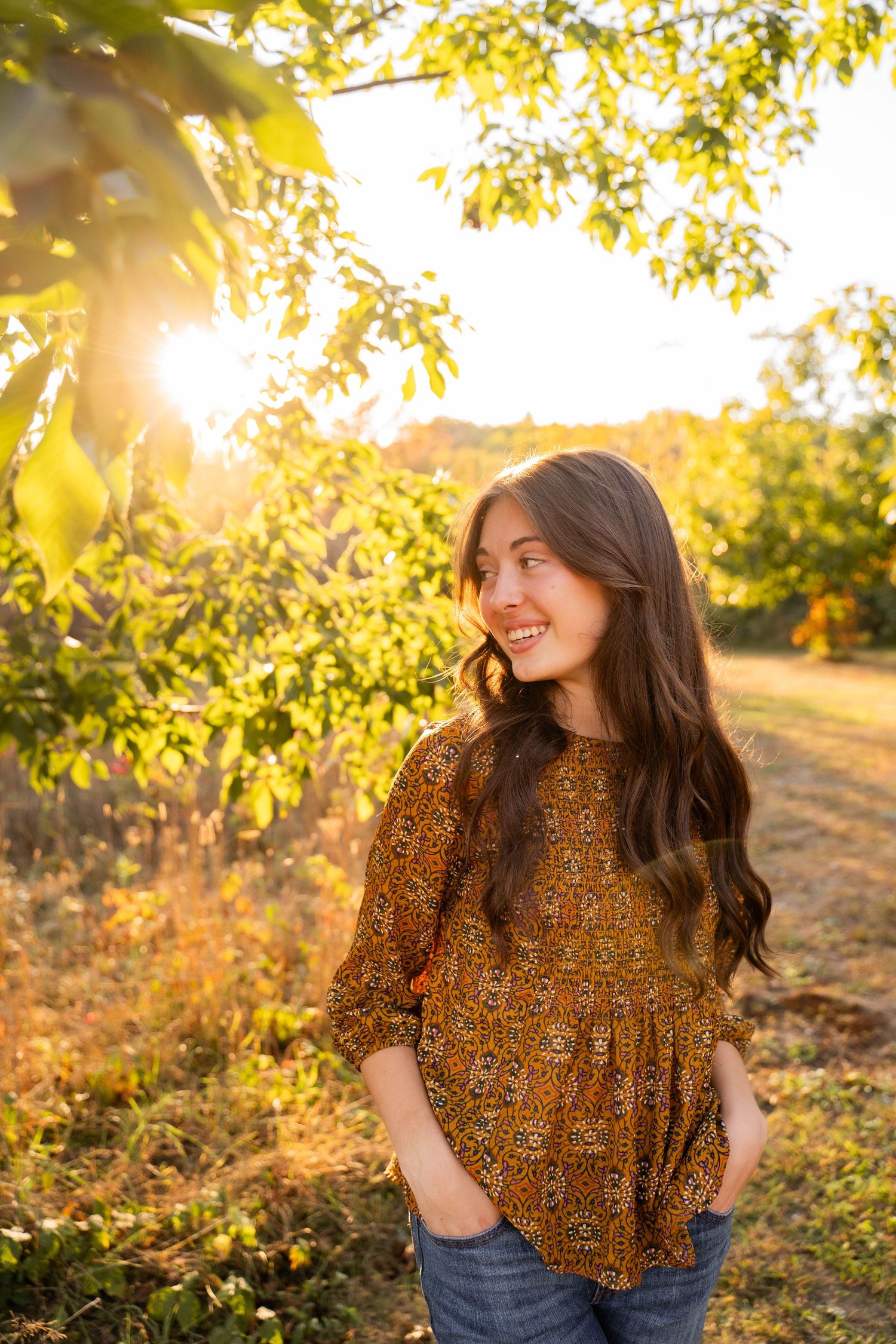 Golden hour portrait session with sunlight streaming through autumn leaves.