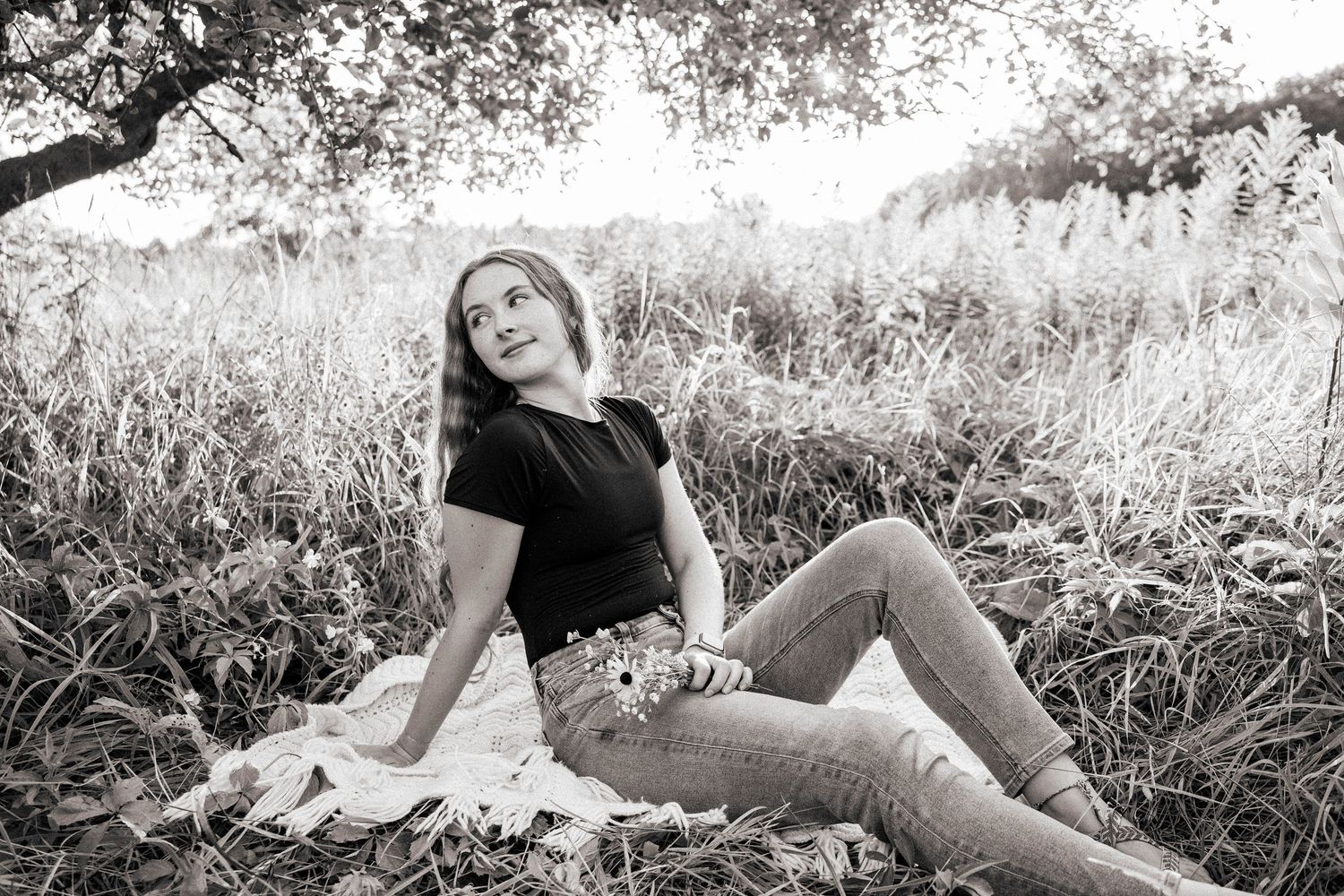 Black and white portraits capture relaxed poses in tall grass during an outdoor photo session.