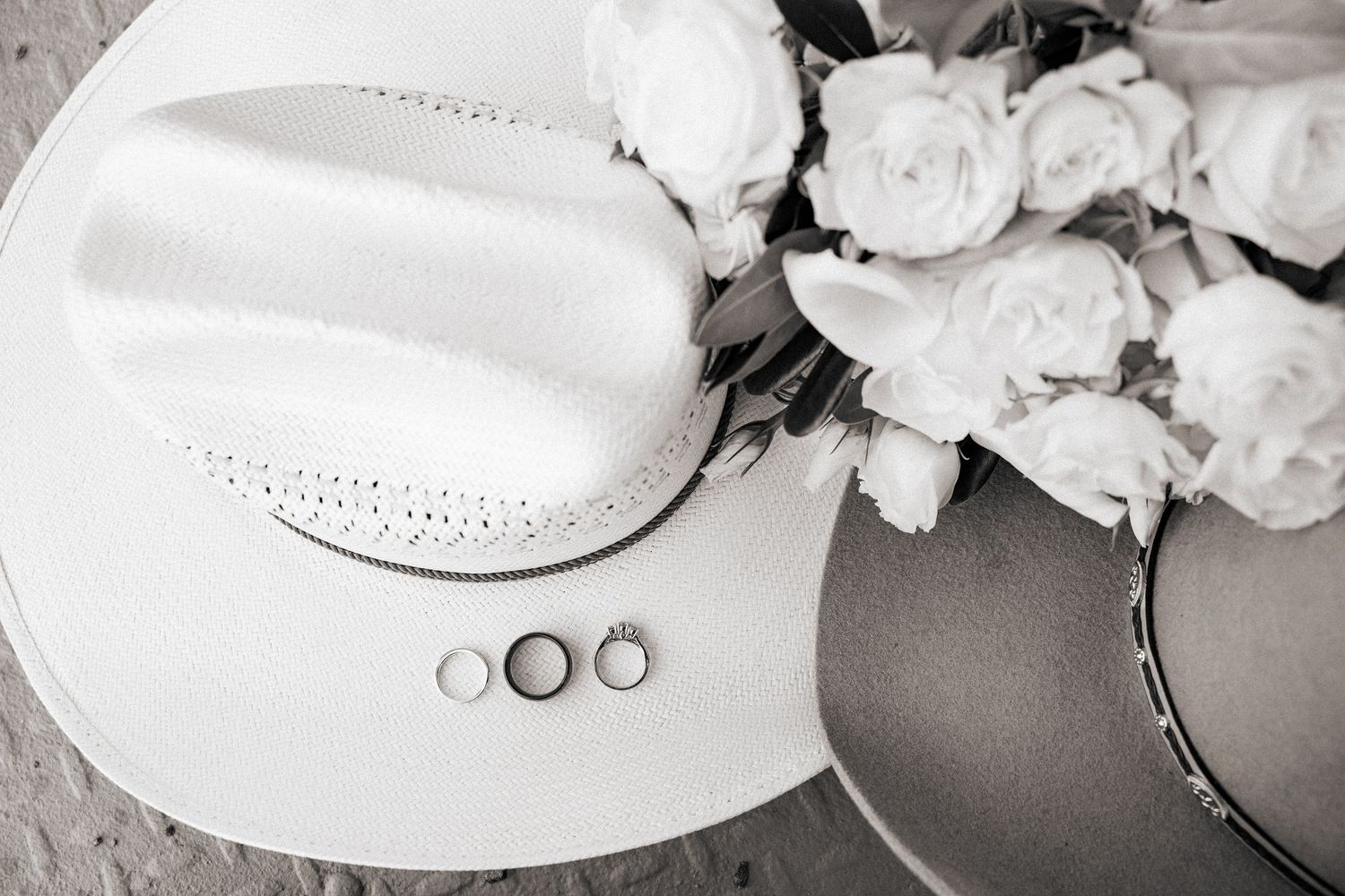 Wedding rings and floral details arranged in minimalist black and white composition.