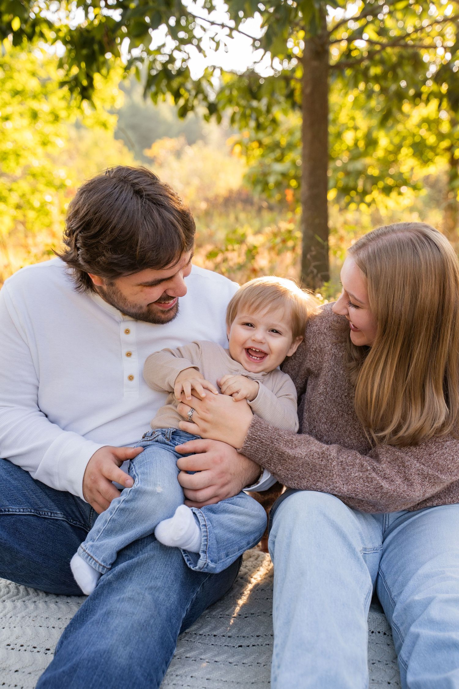 A family shares joyful laughter in a prairie mini session in Eau Claire, Wisconsin on a sunny autumn day outdoors