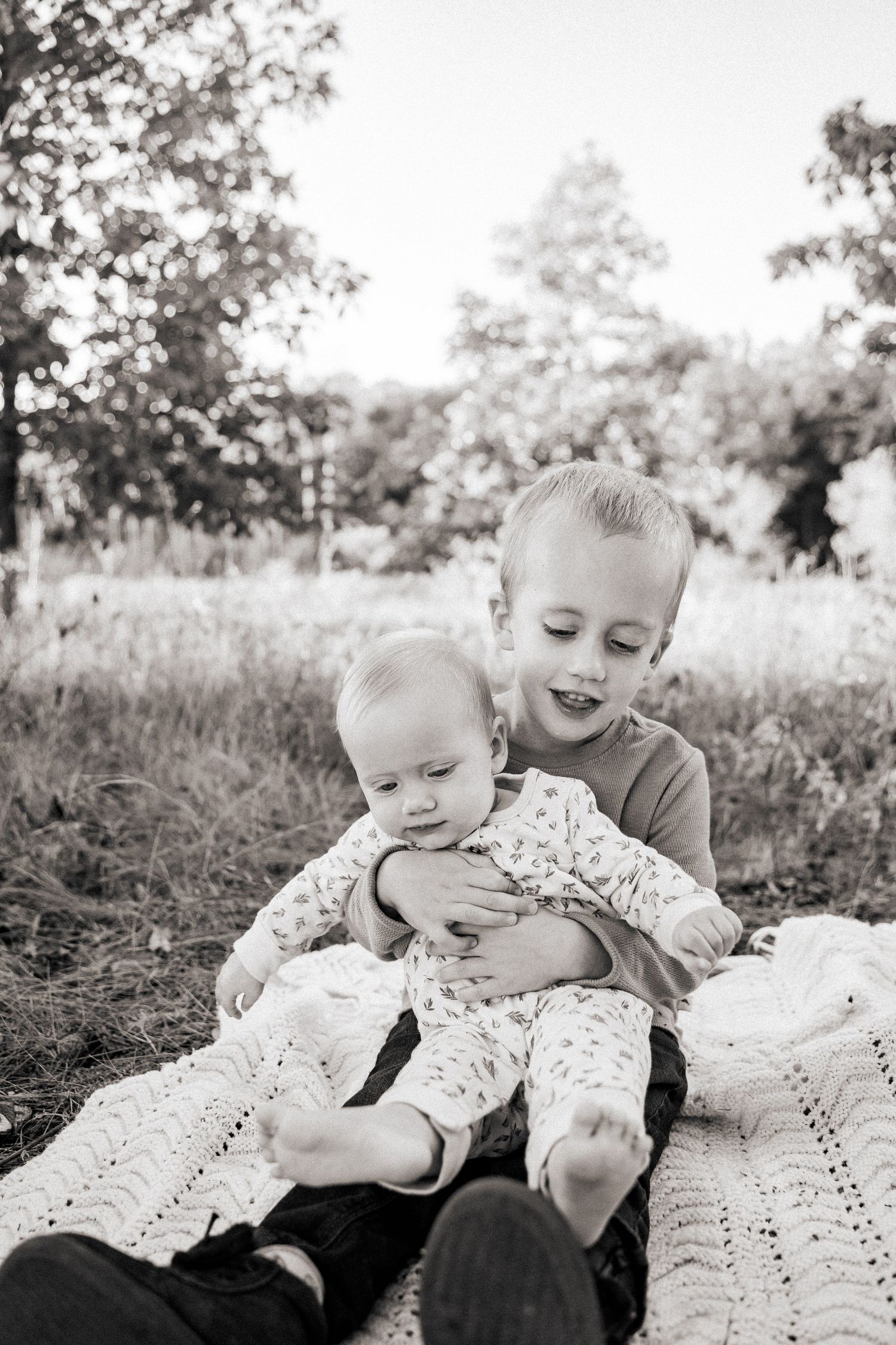 Children laying on a white blanket outdoors in black and white photography in Eau Claire Wisconsin