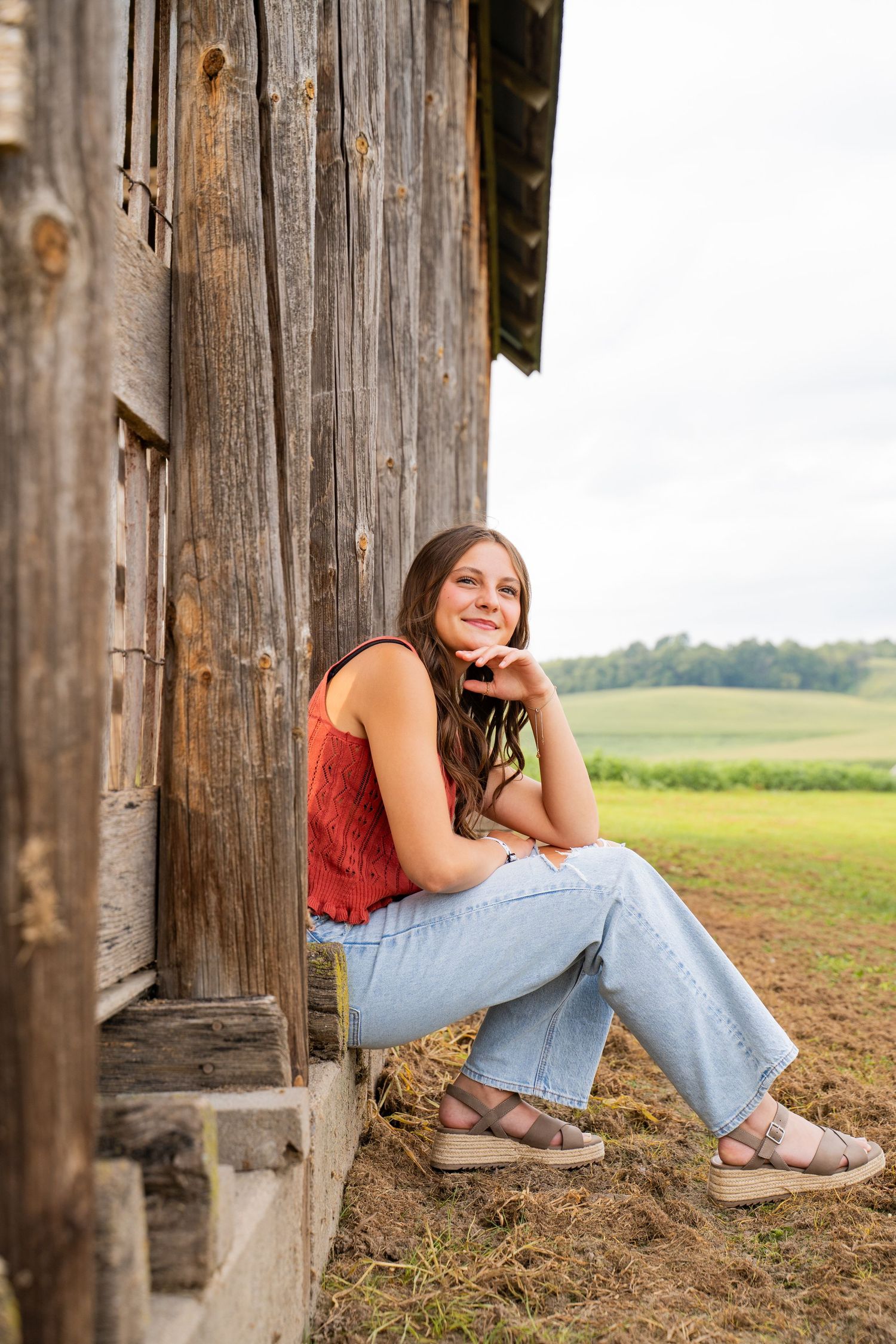 Casual portrait session against rustic wooden barn wall in countryside setting.