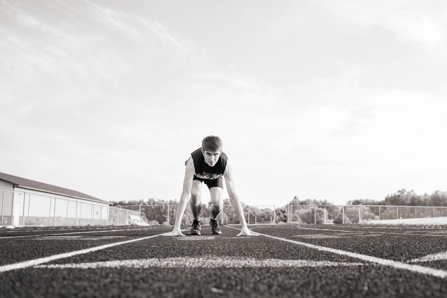 Black and white panoramic shot of person in athletic pose on track field.