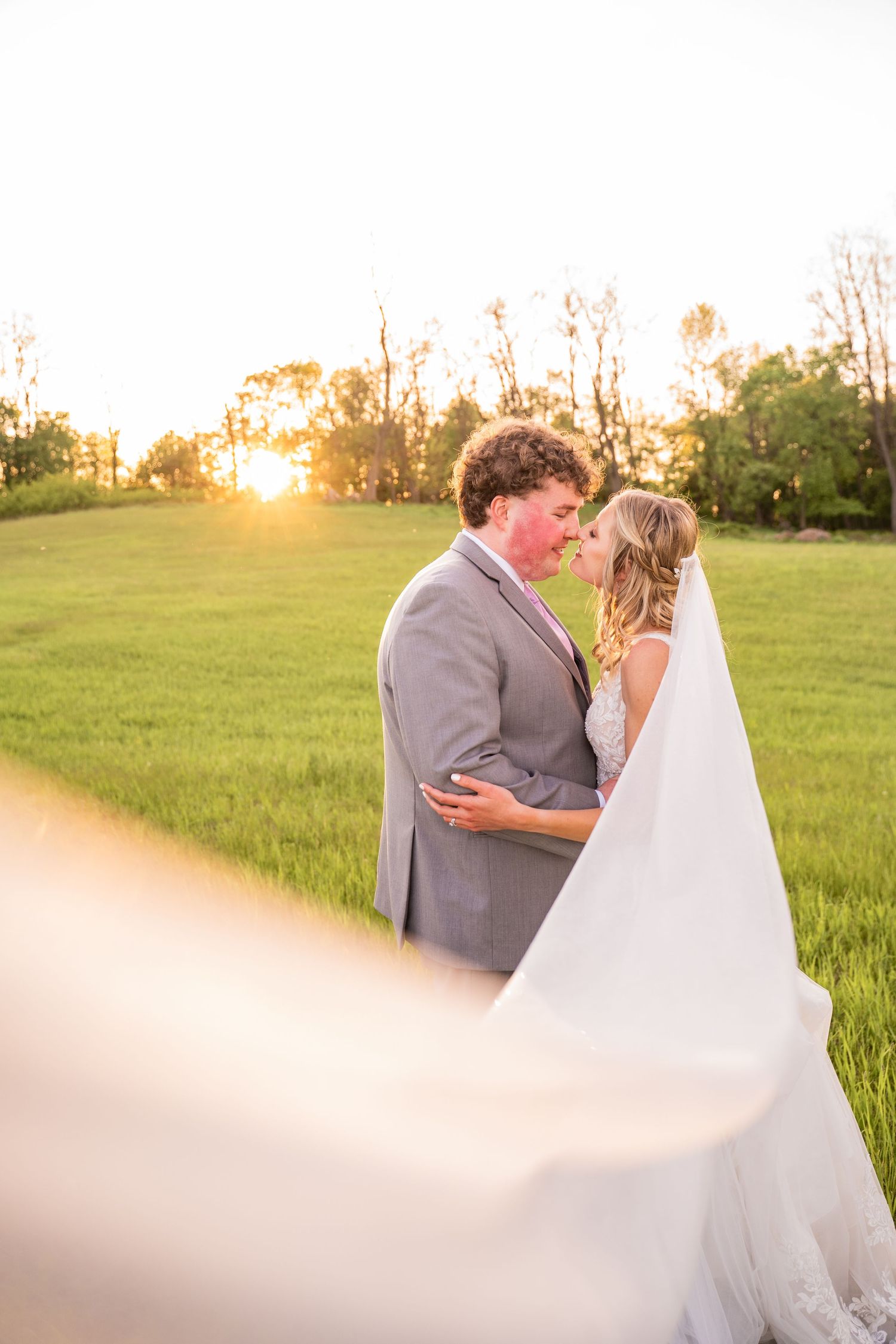 A romantic sunset portrait of newlyweds embracing in a golden field.
